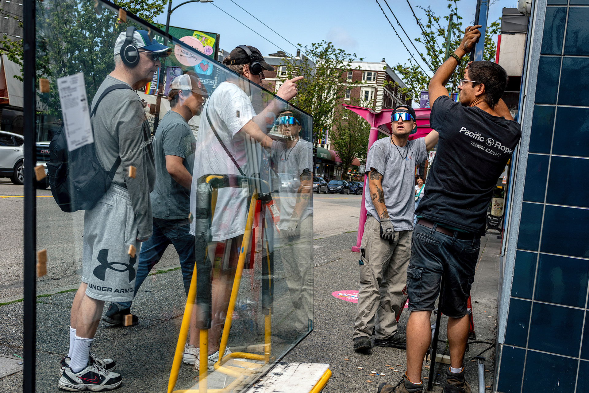 Workerbeing bothered by passerby as they try to replace a broken window.