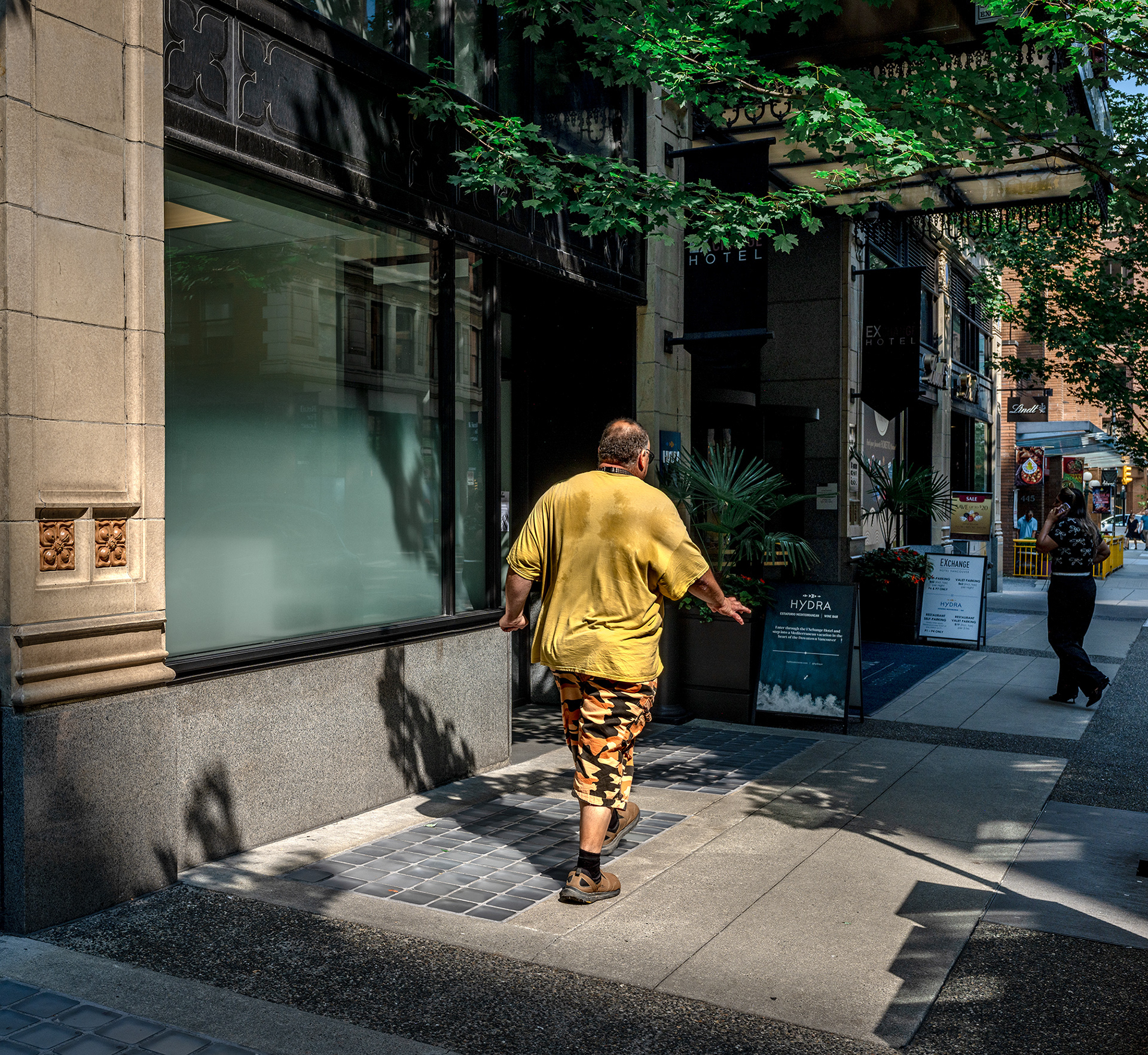 Rambling man in a yellow shirt, walking past the hydra Hotel in Vancouver, its a hot summer day!