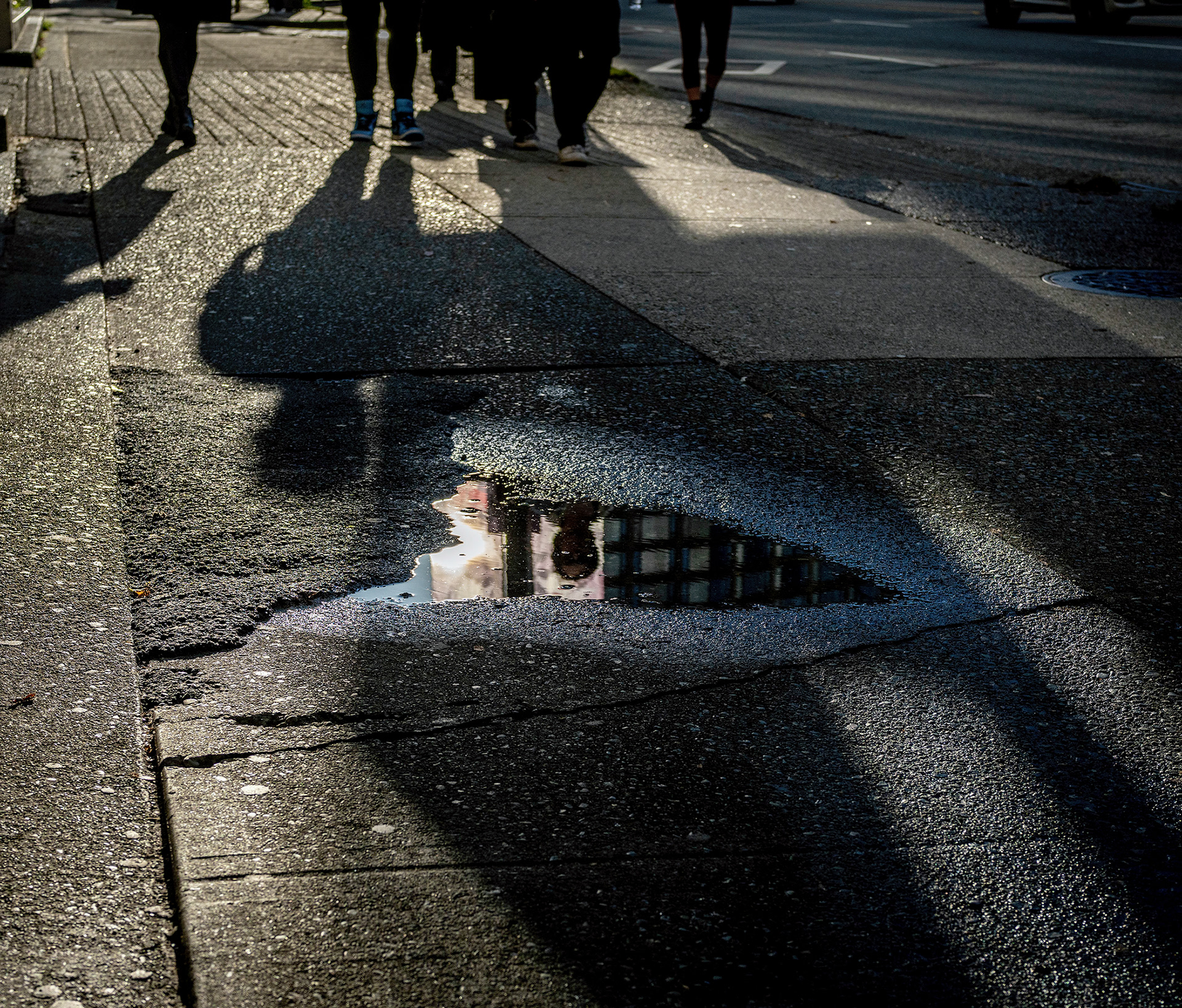 Shadows on a wet sidewalk, reflected face and eyes.