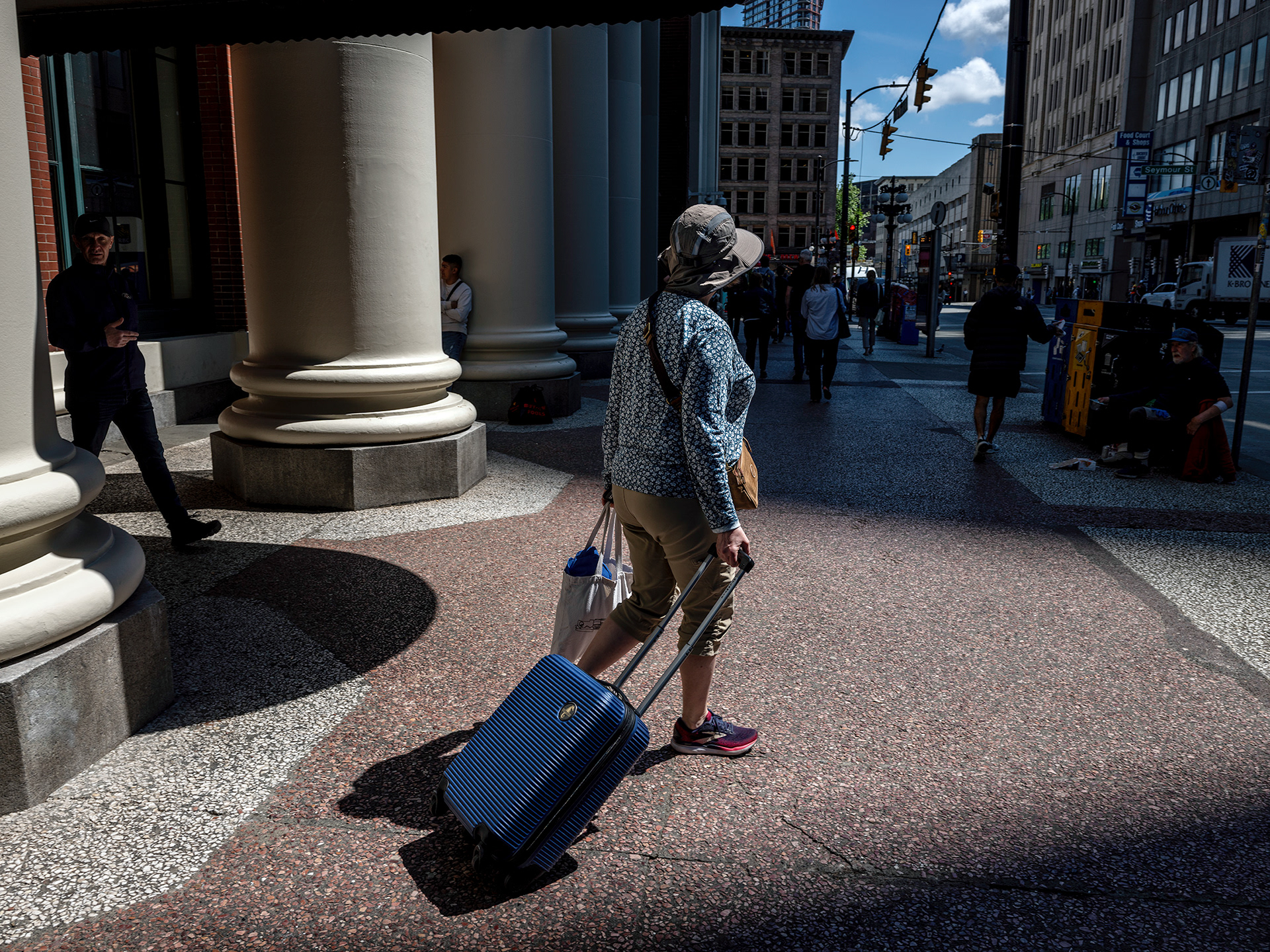 Woman exiting Waterfront Station, Vancouver, towing her blue carry-on bag, distinctive lighting.