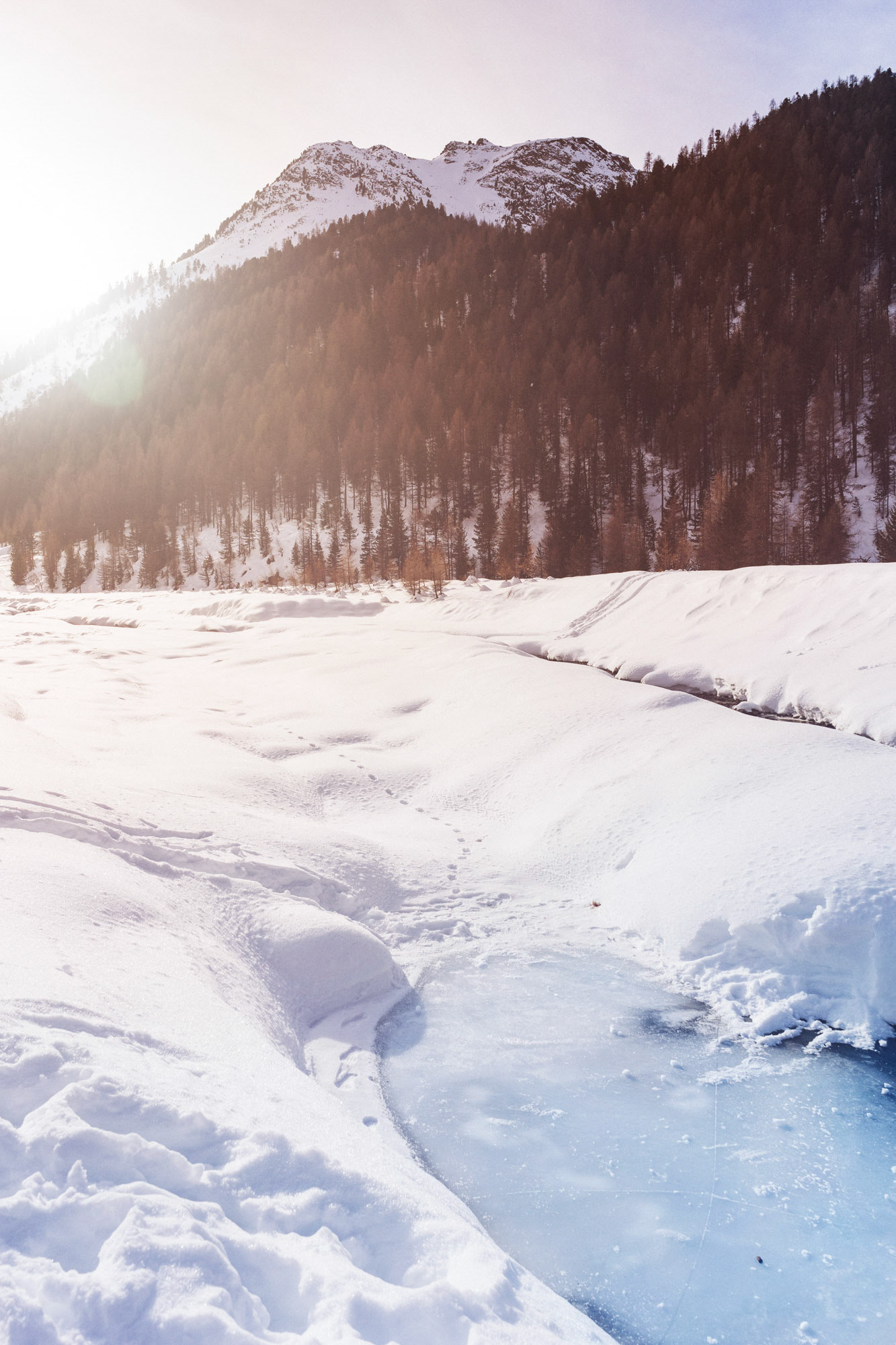 Snowy mountain scene with sun light over the mountains