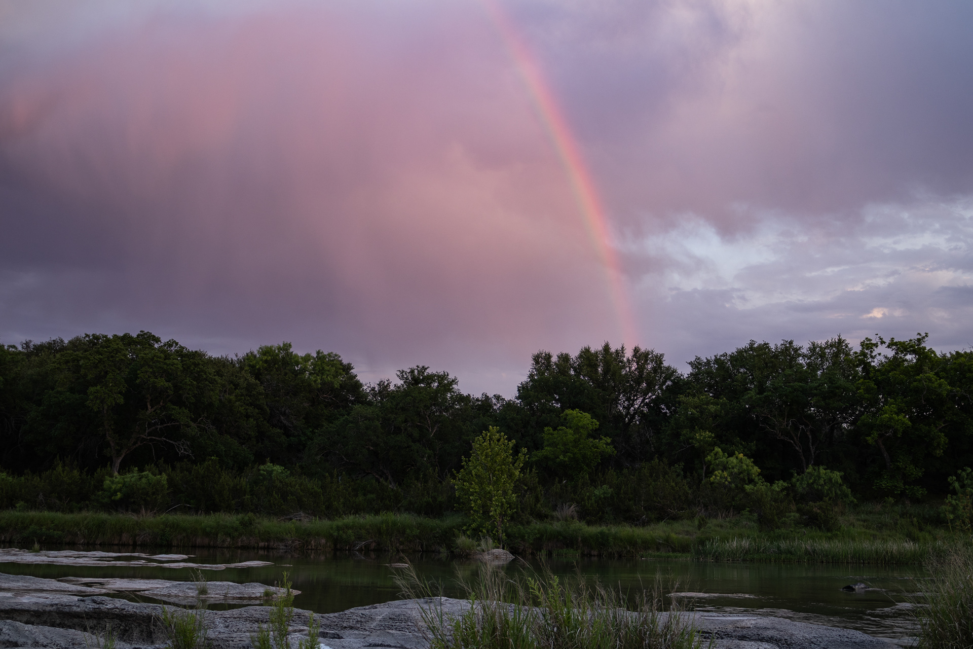 Late evening showers result in a rainbow soaring over the Llano River Ranch in Kimble County, Texas.