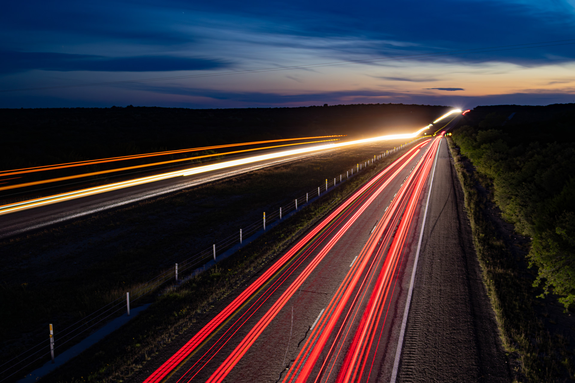 Nighttime vehicle lights trail along Interstate 10 toward the western sky near Roosevelt in Kimble County, Texas.