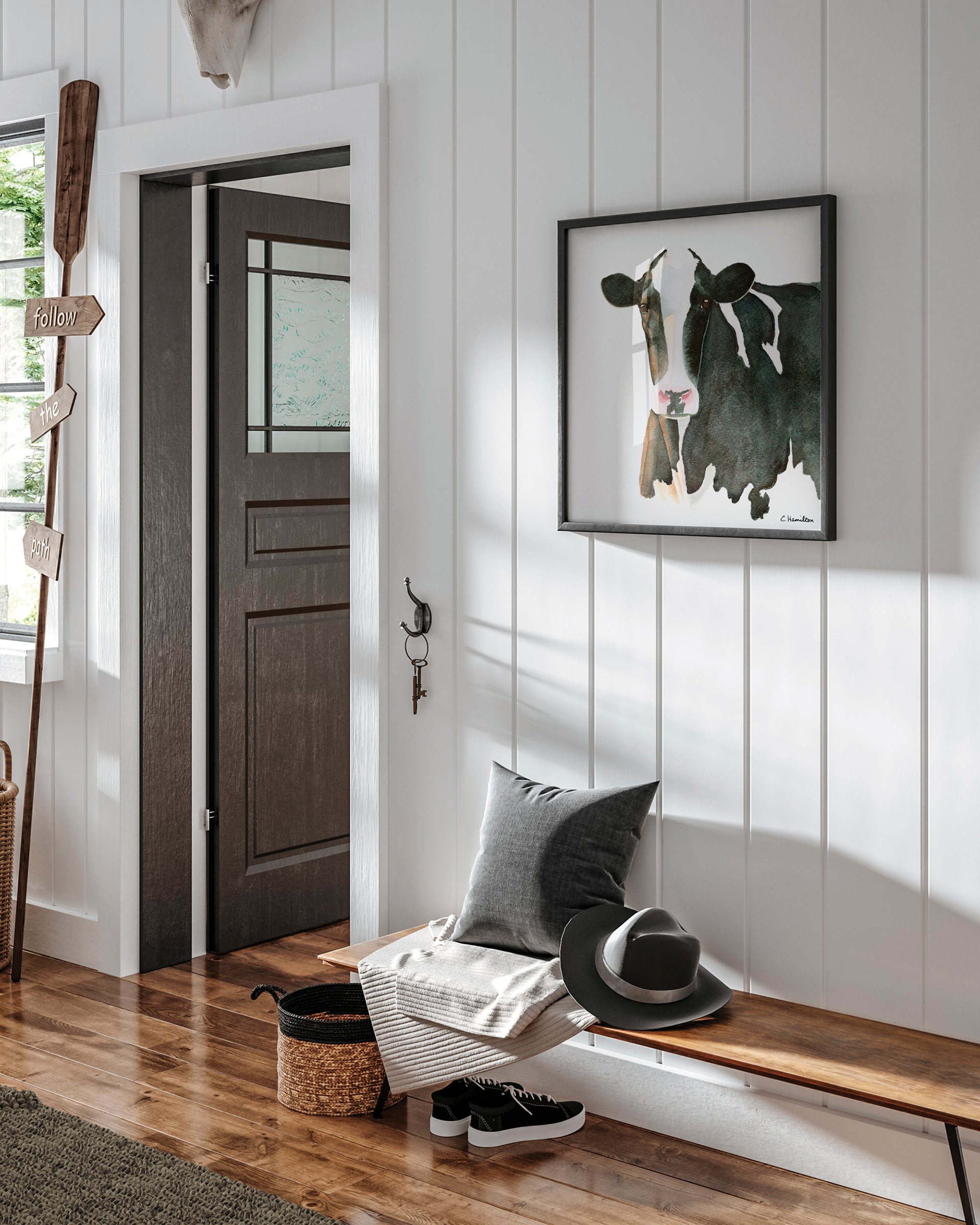 Farmhouse style entryway with framed watercolor fine art print of a holstein cow hanging on the wall over a bench.
