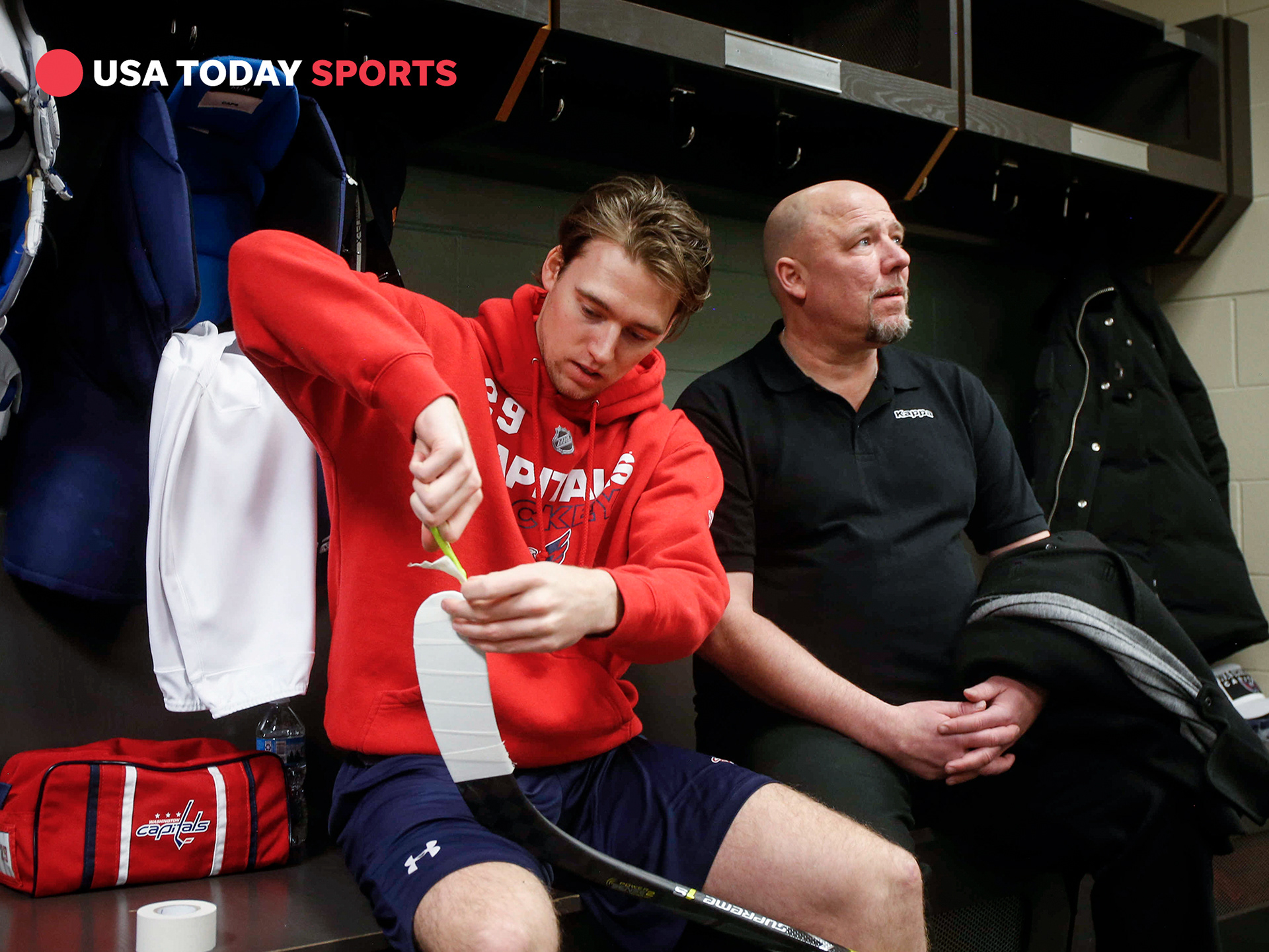 Washington Capitals defenseman Christian Djoos tapes his hockey stick as his father, Par, a former defenseman for the Detroit Red Wings and New York Rangers, joins him in the locker room prior to a team meeting on Thursday, Feb. 15, 2018, in St. Paul, Minn.