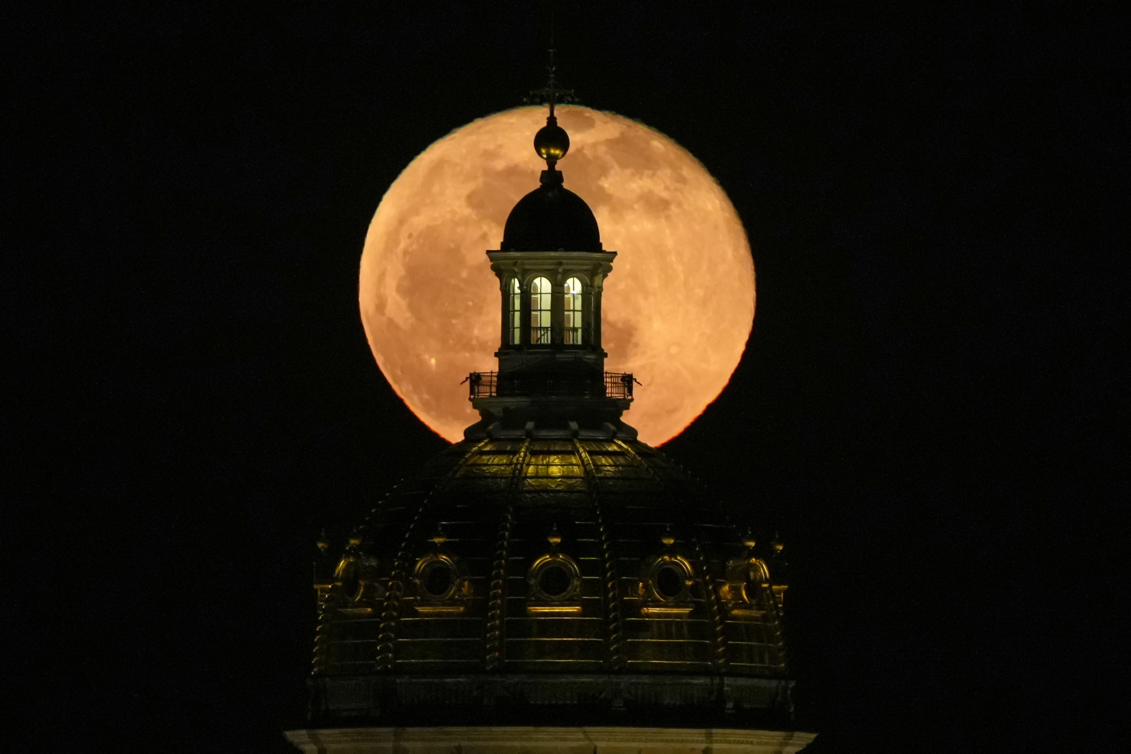The full moon rises behind the Iowa Capitol Building in Des Moines, Iowa, on Thursday, April 6, 2023. 