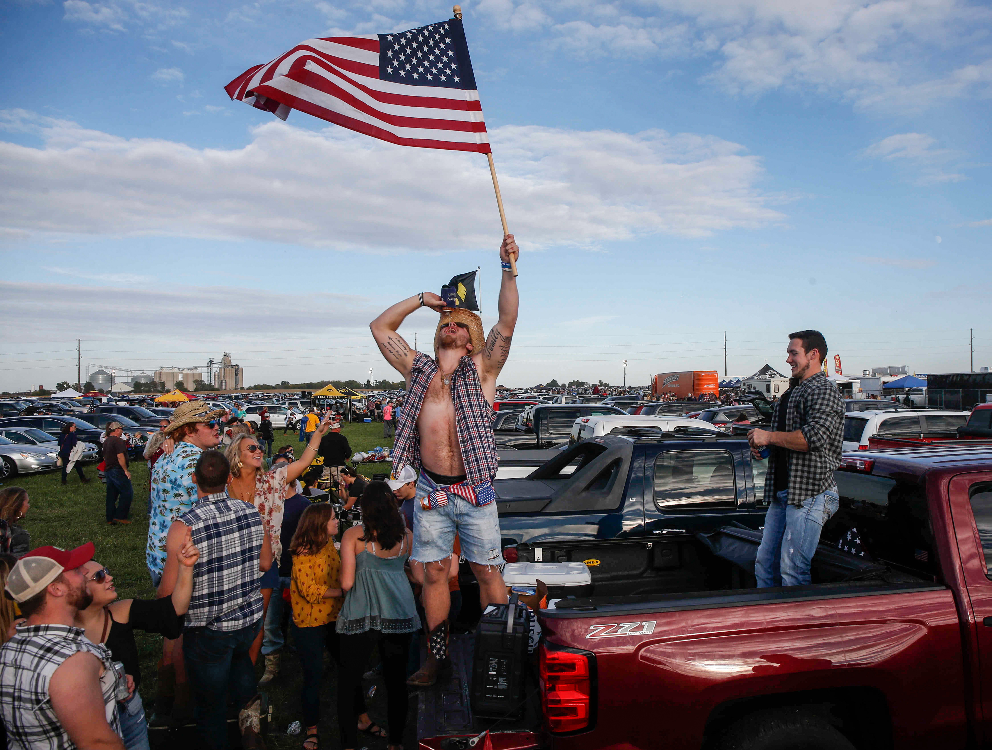 Ashton Clemons of Boone raises a U.S. flag from the back of a truck as his friends have fun tailgating in the parking lot before the Luke Bryan concert in Boone on Friday, Sept. 30, 2017.