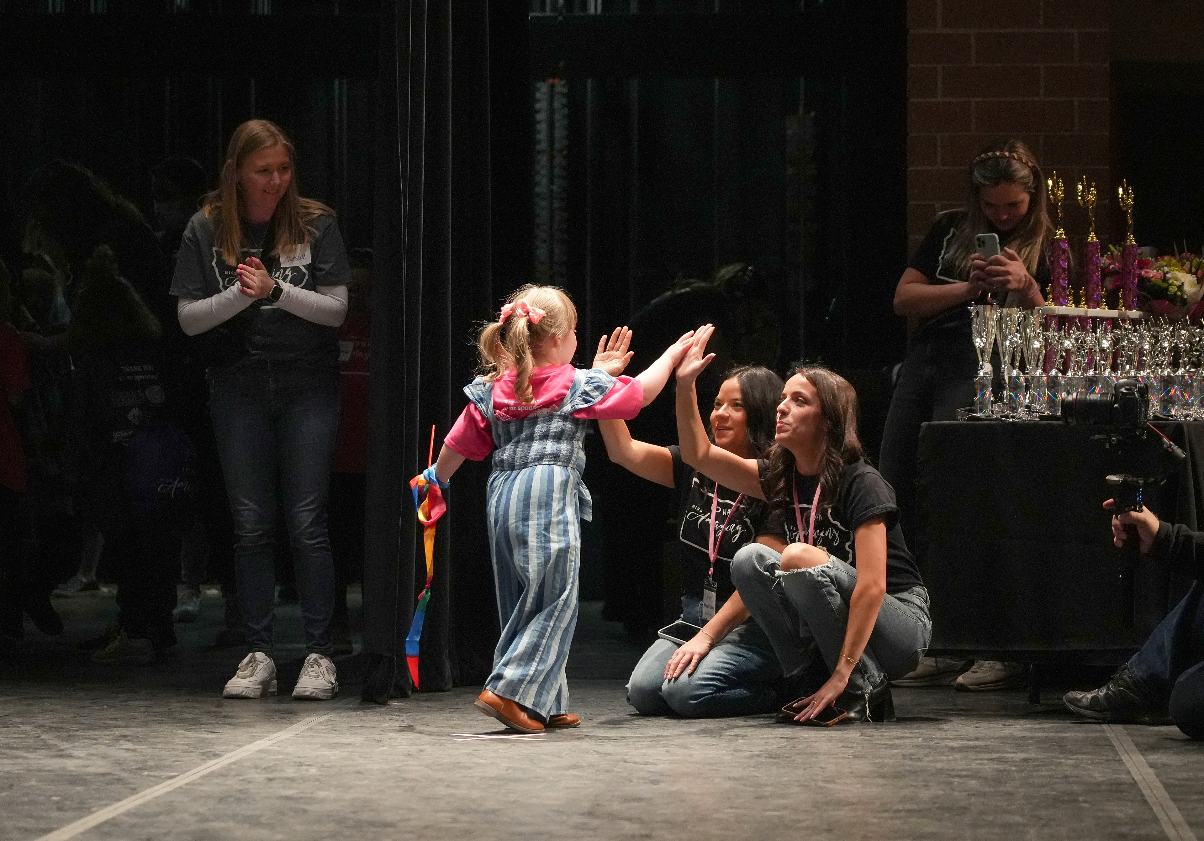 Iowa Miss Amazing rising star participant Quinn Bexten gives high-fives to co-directors Laura Tooley, right, and Morgan Tooley after warming up on stage prior to her passion project during the 11th Annual Iowa Miss Amazing pageant on Saturday, Feb. 4, 2023, in Urbandale, Iowa.