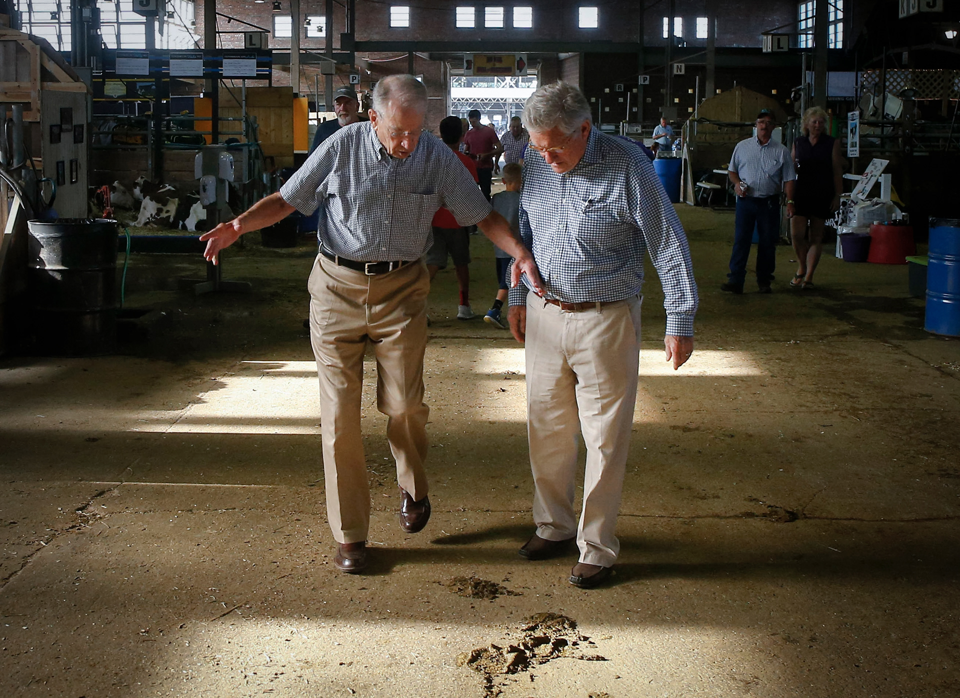 U.S. Sen. Charles Grassley (R-Iowa), left, warns Fred Barnes, a reporter at the Washington Weekly Standard, about a cow pie in the hallway of the dairy barn on Friday, Aug. 10, 2018, at the Iowa State Fair in Des Moines.