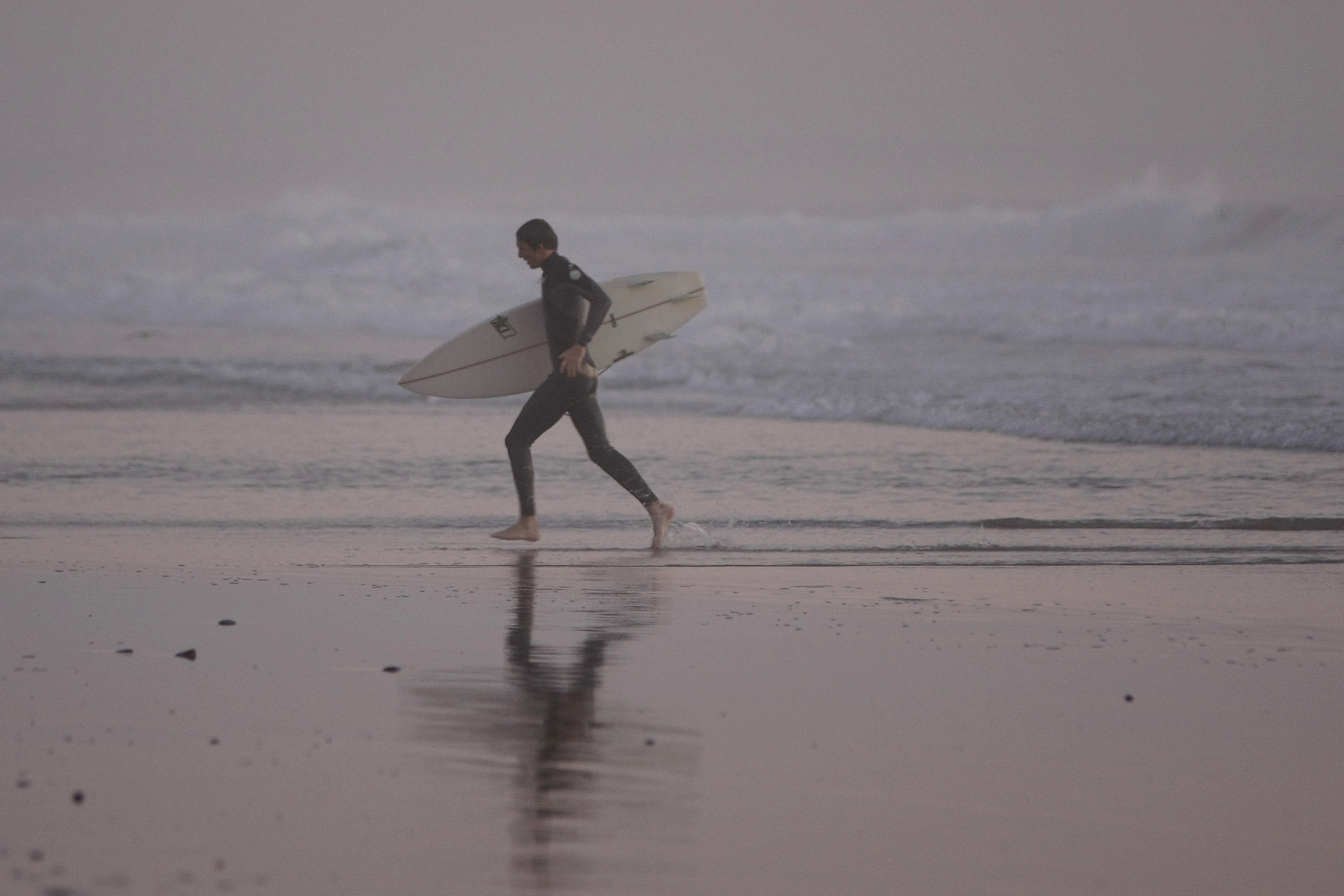 A surfer makes his way out of the water after a surf session on January 18, 2011, in Oceanside, Calif.