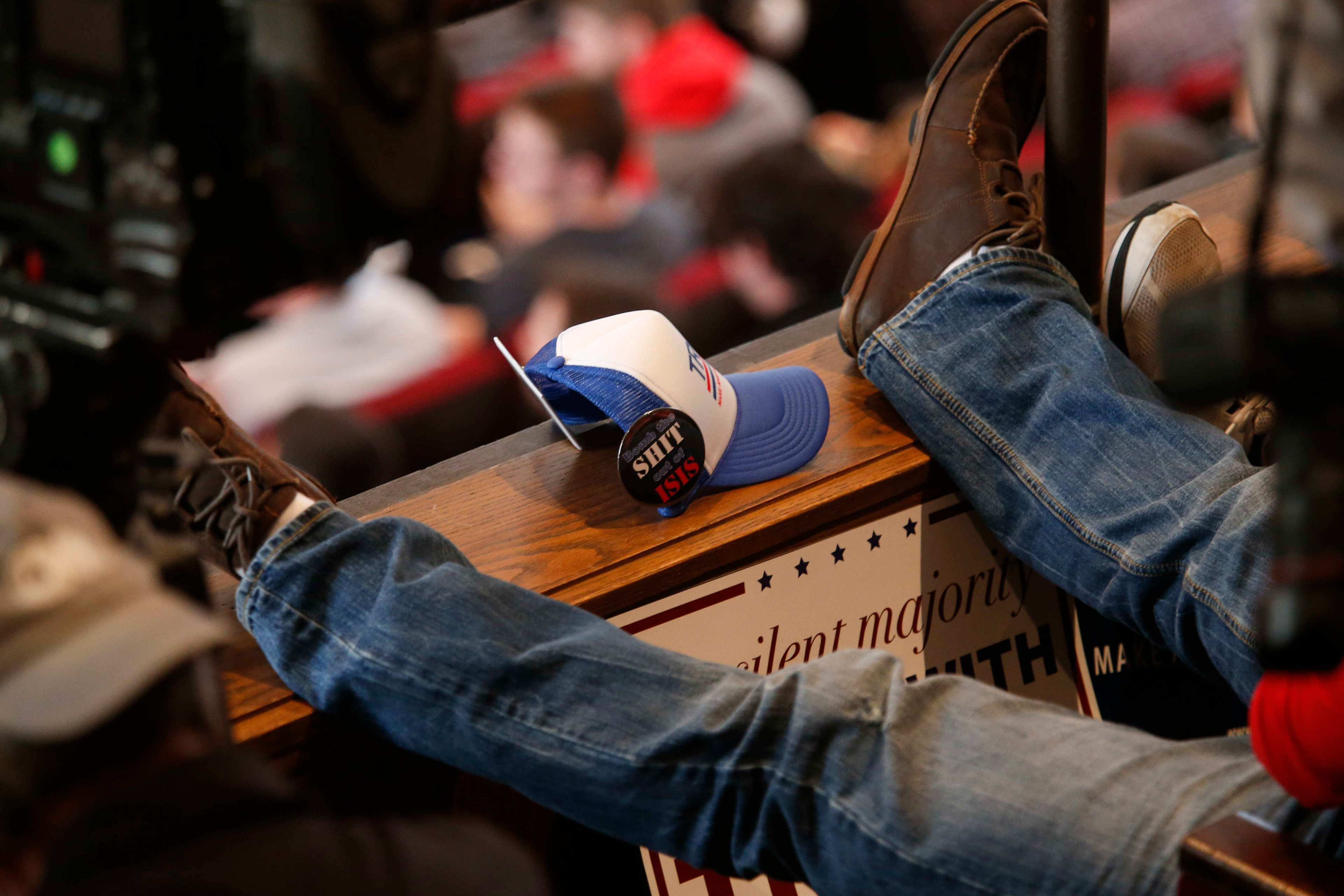 A supporter of Republican presidential candidate Donald Trump rests his feet with campaign items between his feet at Central College on Saturday, Jan. 23, 2016, in Pella, Iowa.