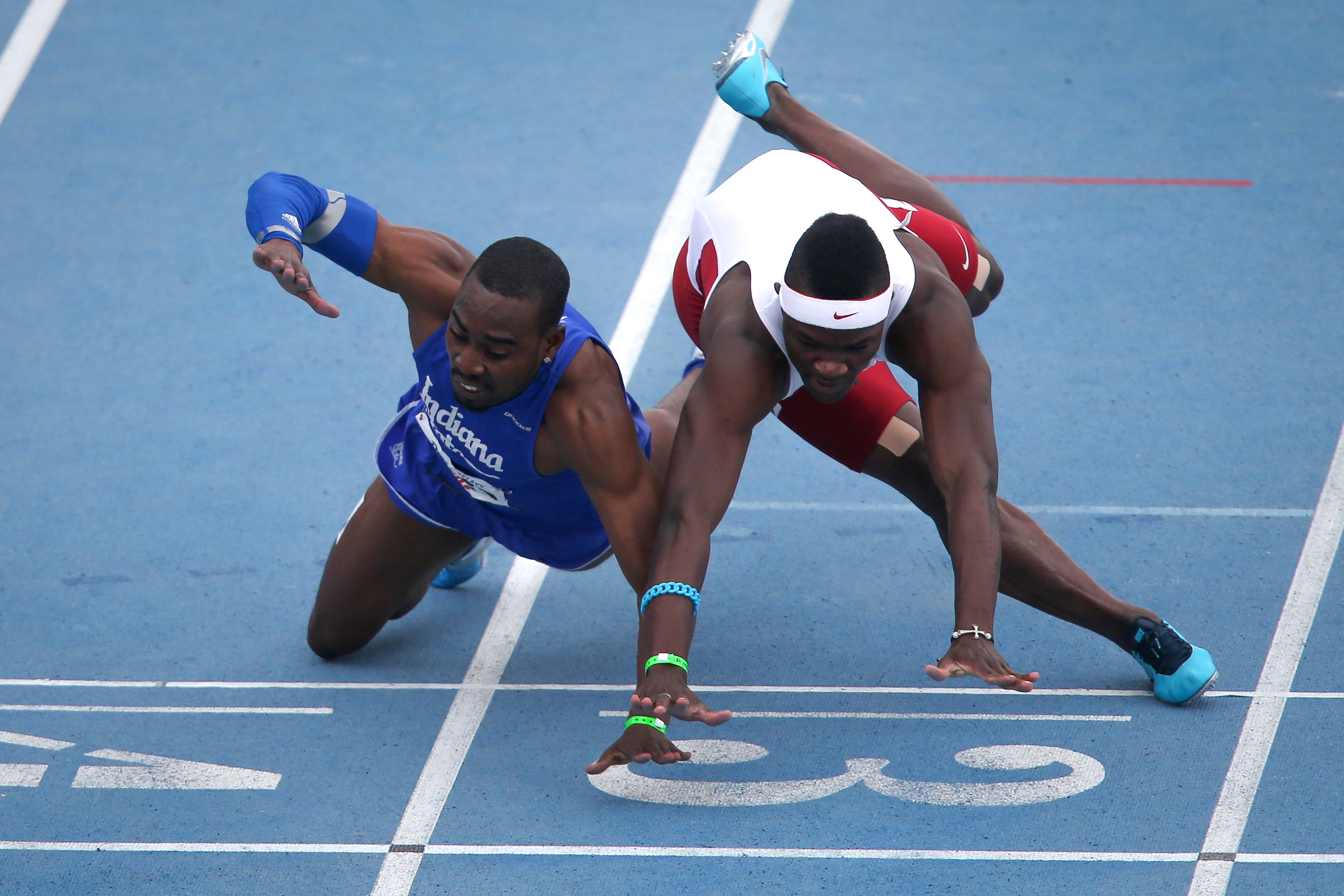 Runners fall across the finish line in the 100-meter during Drake Relays on Saturday, April 26, 2014, at Drake Stadium in Des Moines, Iowa.