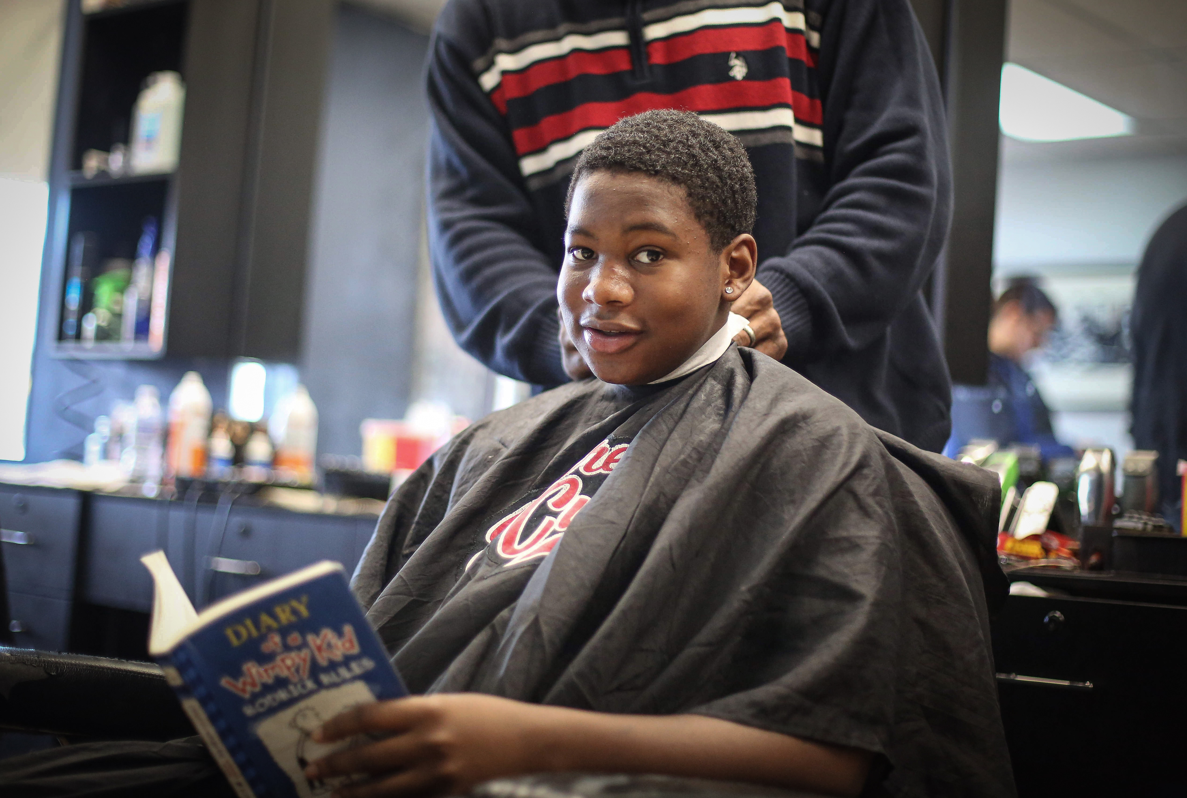 Barber Lance Williams Sr, cuts the hair of Djalin Marshall, 15, of Des Moines, as Marshall reads a book during Storybook Sundays at Supreme Cuts in Des Moines on Sunday, Feb. 16, 2020. Williams began Storybook Sundays as a way to help the Des Moines community improve literacy. 