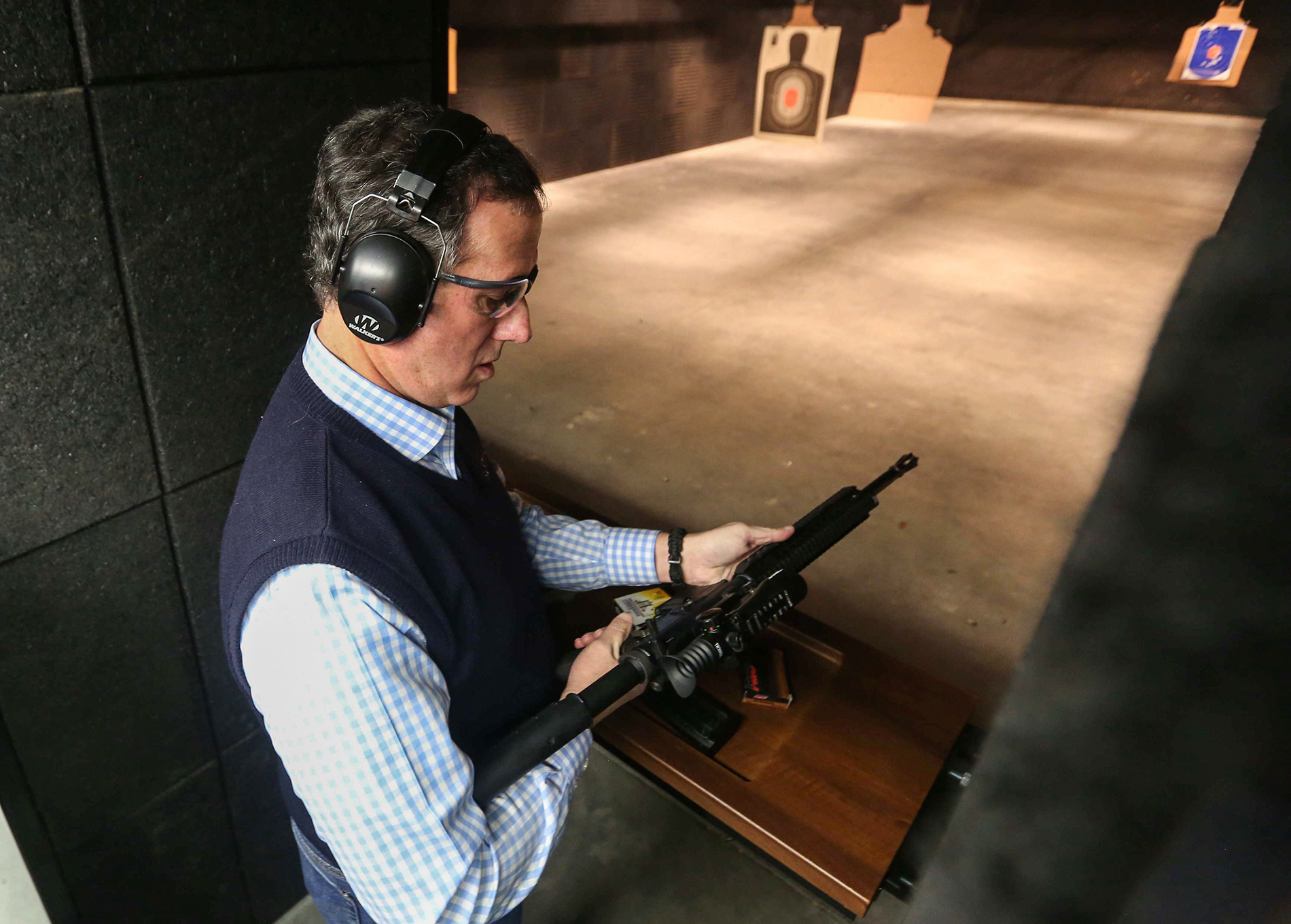Republican presidential candidate Rick Santorum looks over an AR-style rifle before shooting it at the Central Iowa Impact indoor gun range in Boone.
