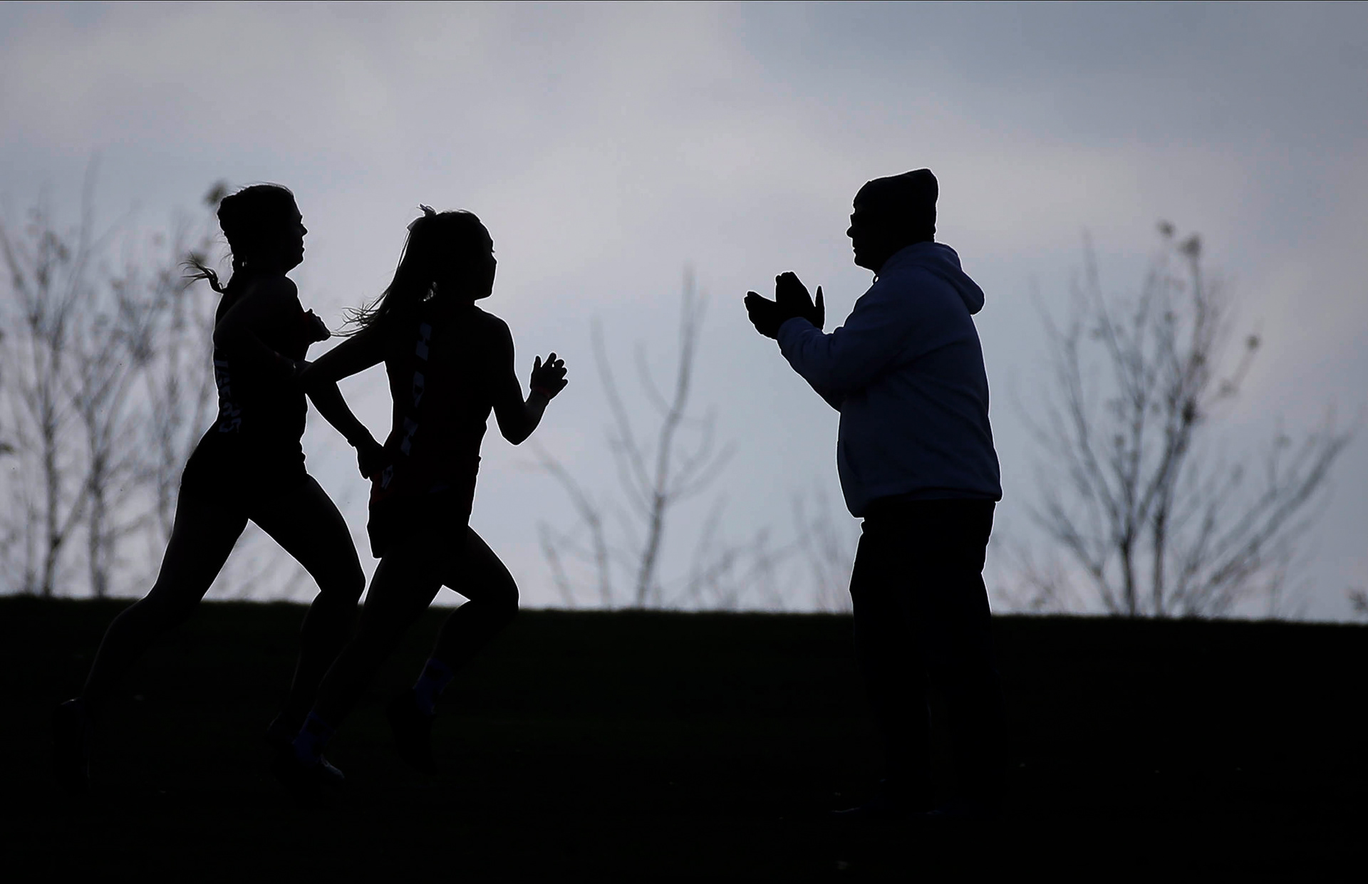 Runners make their way along the route as a fan cheers them on during the Class 3A Iowa high school state cross country meet on Friday, Oct. 29, 2021, in Fort Dodge.