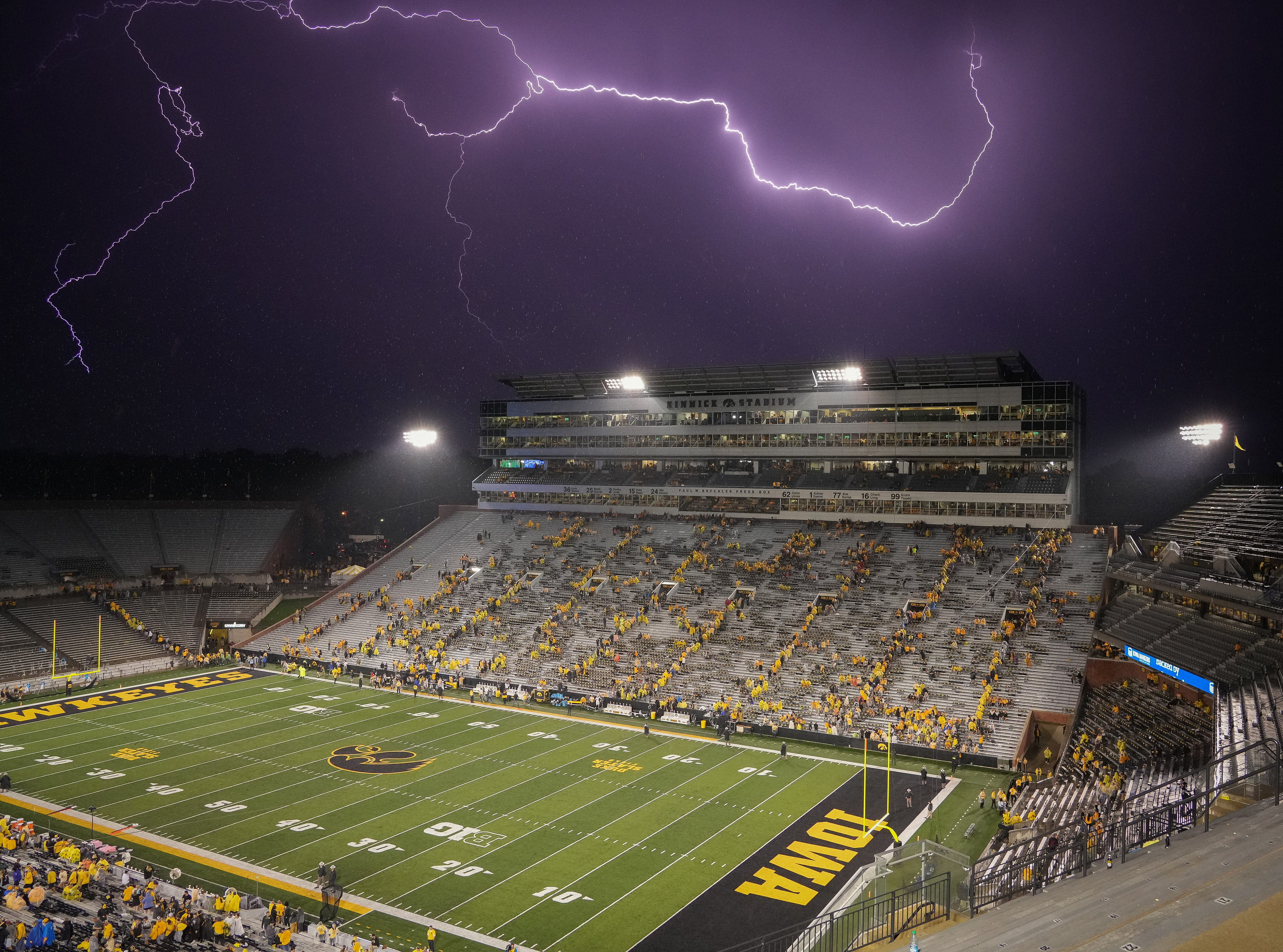 Football fans evacuate Kinnick Stadium as a bolt of lightning flashes overhead during a weather delay in the third quarter of Iowa's non-conference NCAA football game against Nevada on Saturday, Sept. 17, 2022, in Iowa City, Iowa.