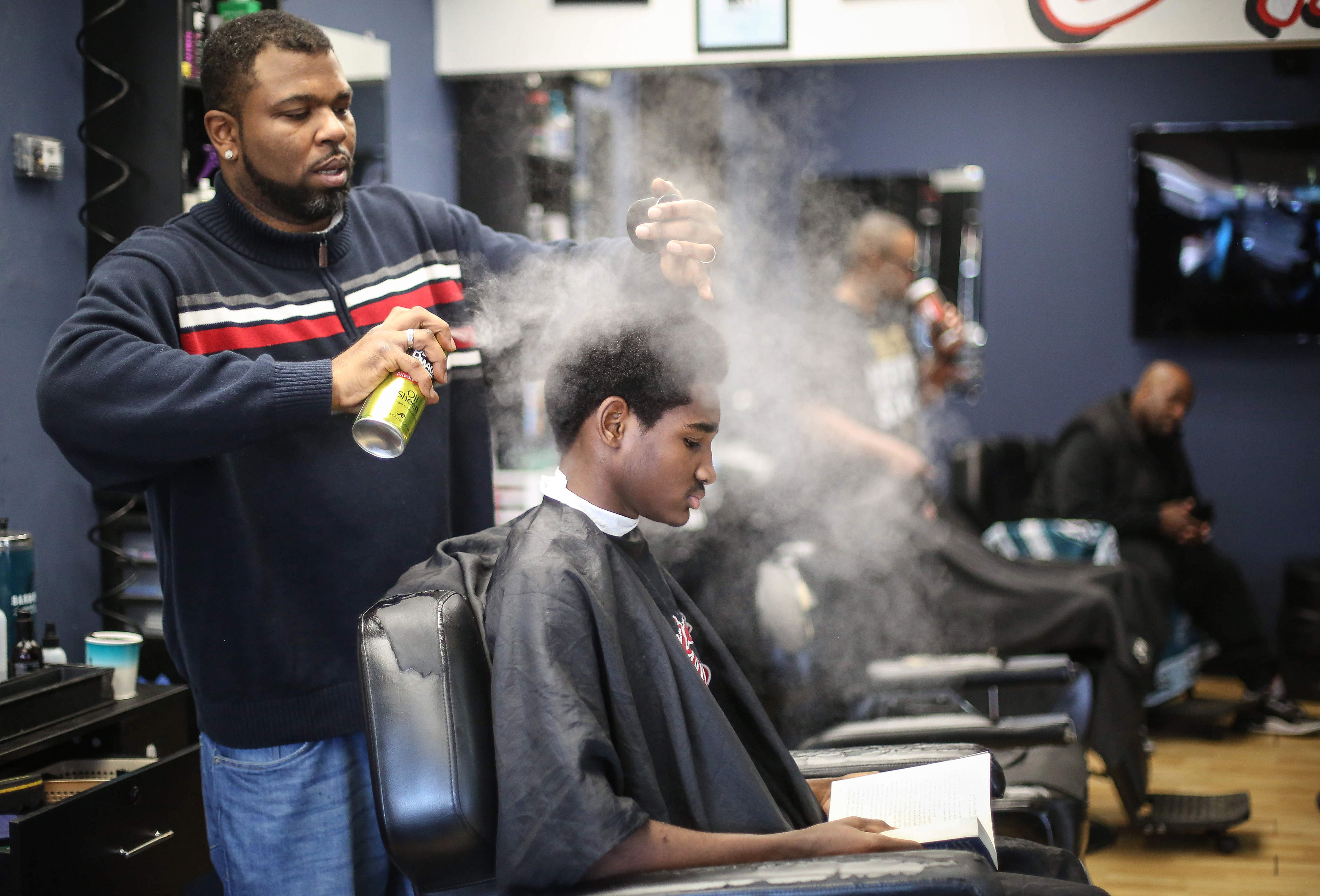 Barber Lance Williams Sr, sprays the hair of Aronta Johnson, 13, of Des Moines, as Johnson reads a book during Storybook Sundays at Supreme Cuts in Des Moines on Sunday, Feb. 16, 2020. Williams began Storybook Sundays as a way to help the Des Moines community improve literacy. 