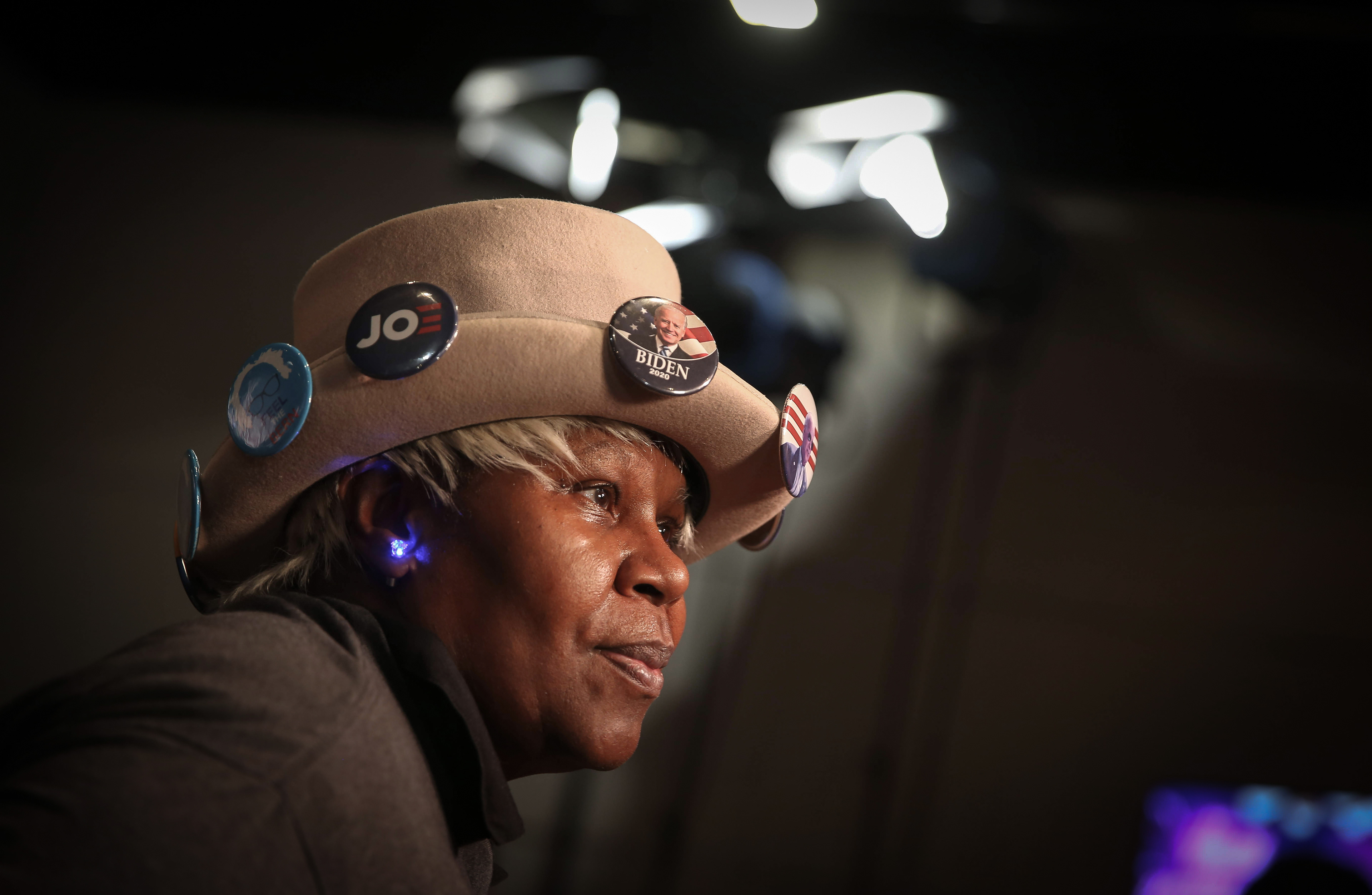 Joann Smith, a Joe Biden superfan from Chicago, wears a hat with several campaign buttons for Biden and her third choice, Bernie Sanders, during the caucus party for Joe Biden at the Olmstead Building at Drake University in Des Moines on Monday, Feb. 3, 2020.