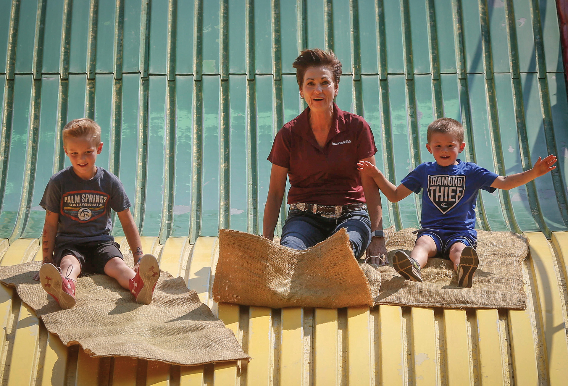 Iowa Gov. Kim Reynolds races her grandchildren Rush Fagan, left, and Kruze Fagan, down the Giant Slide on Thursday, Aug. 9, 2018, during the Iowa State Fair in Des Moines.