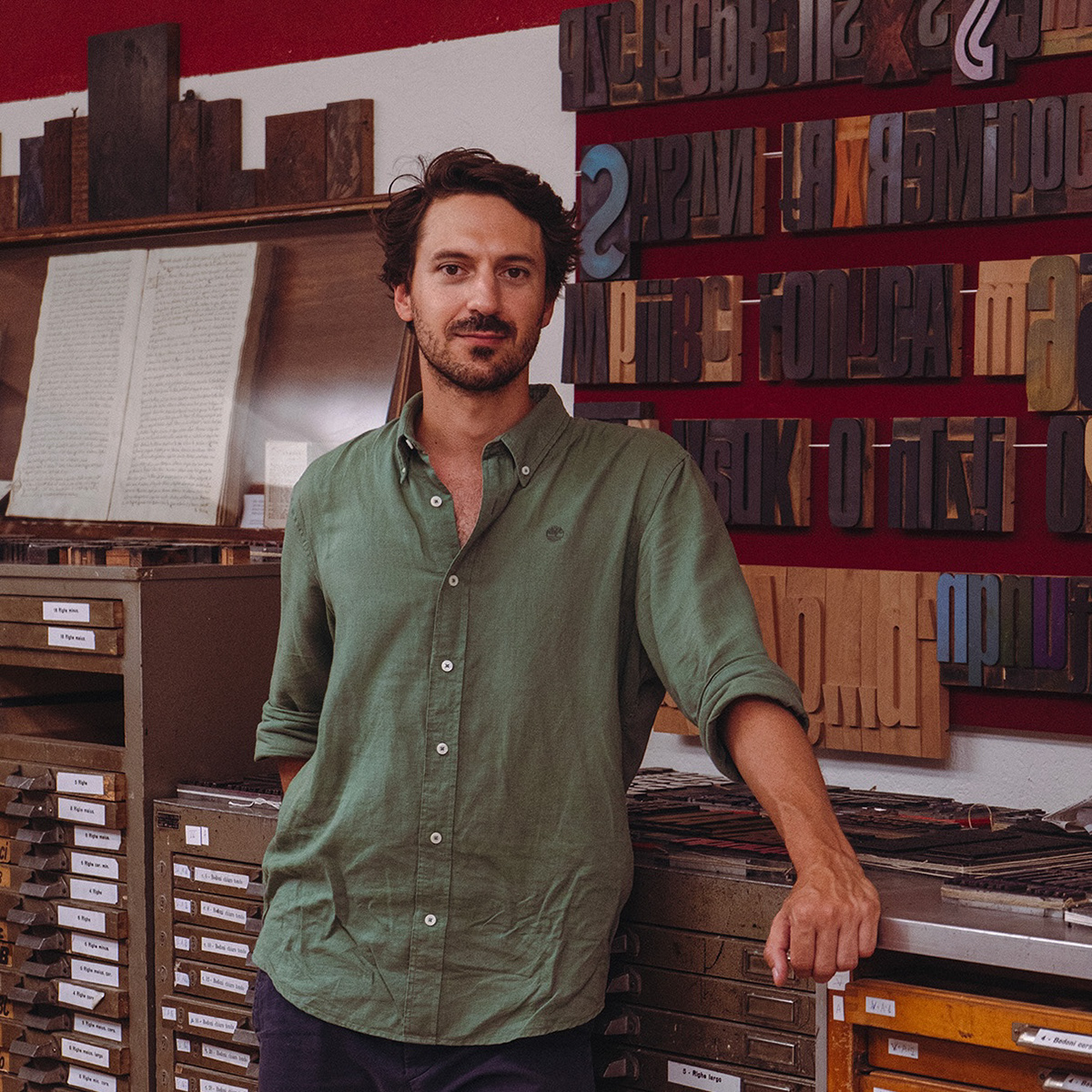 Ritratto fotografico di Stefano Grassi circondato dai caratteri mobili del museo della Stampa di Artogne.