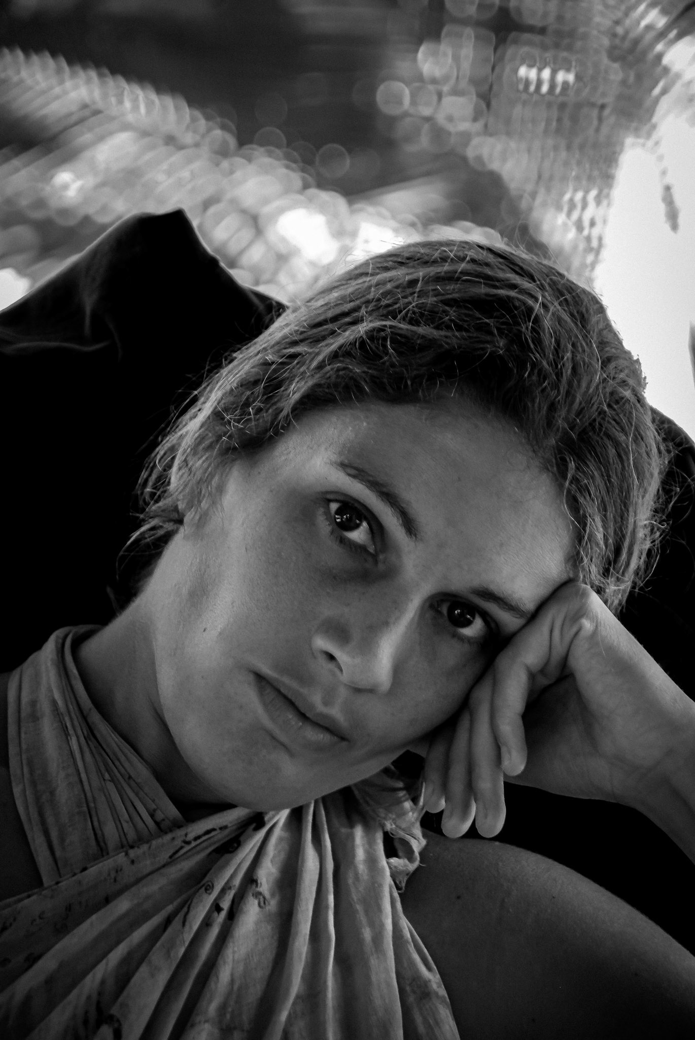 Intimate black-and-white portrait of a woman resting her head on her hand in soft available light.