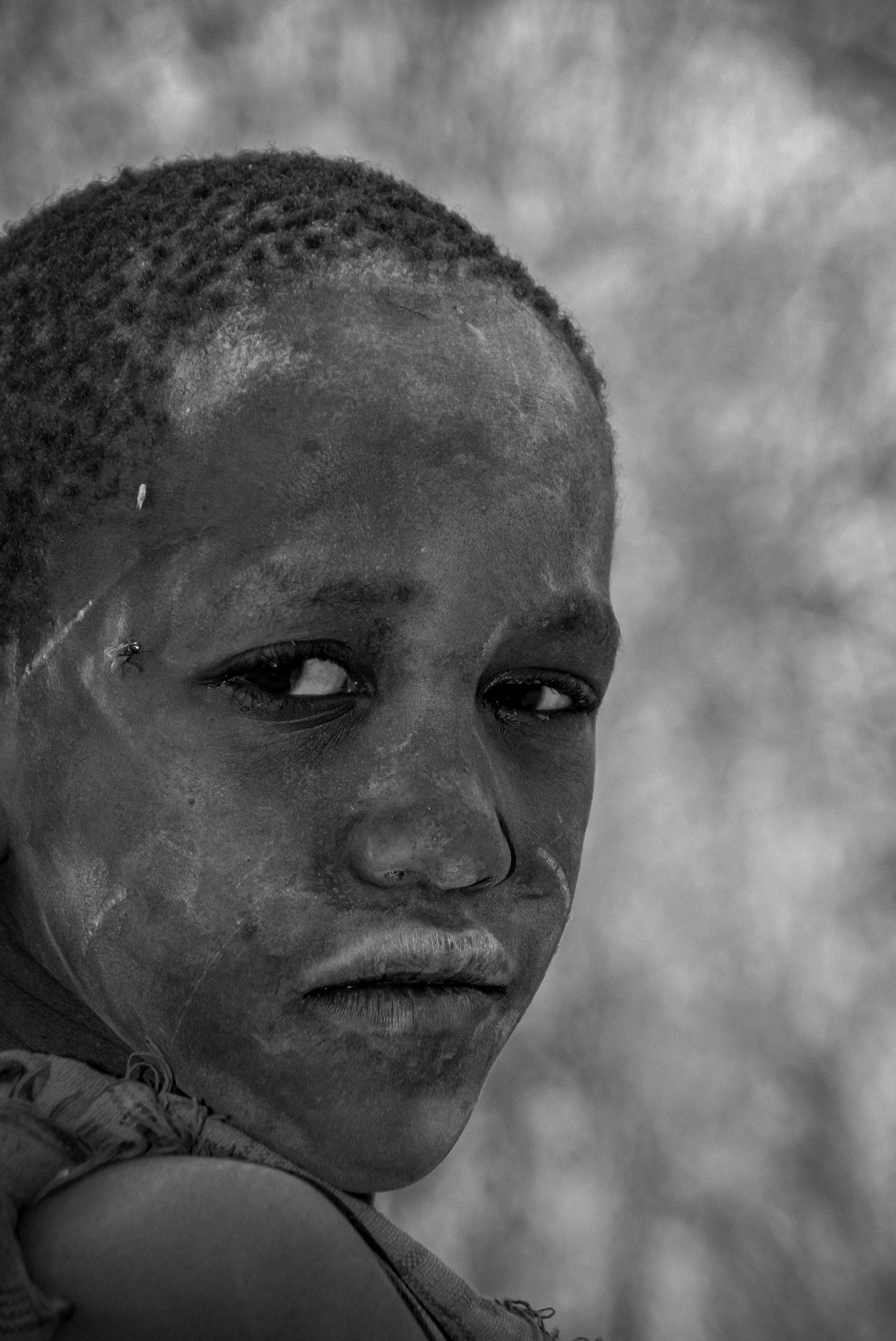 Close black-and-white portrait of a child in soft natural light.