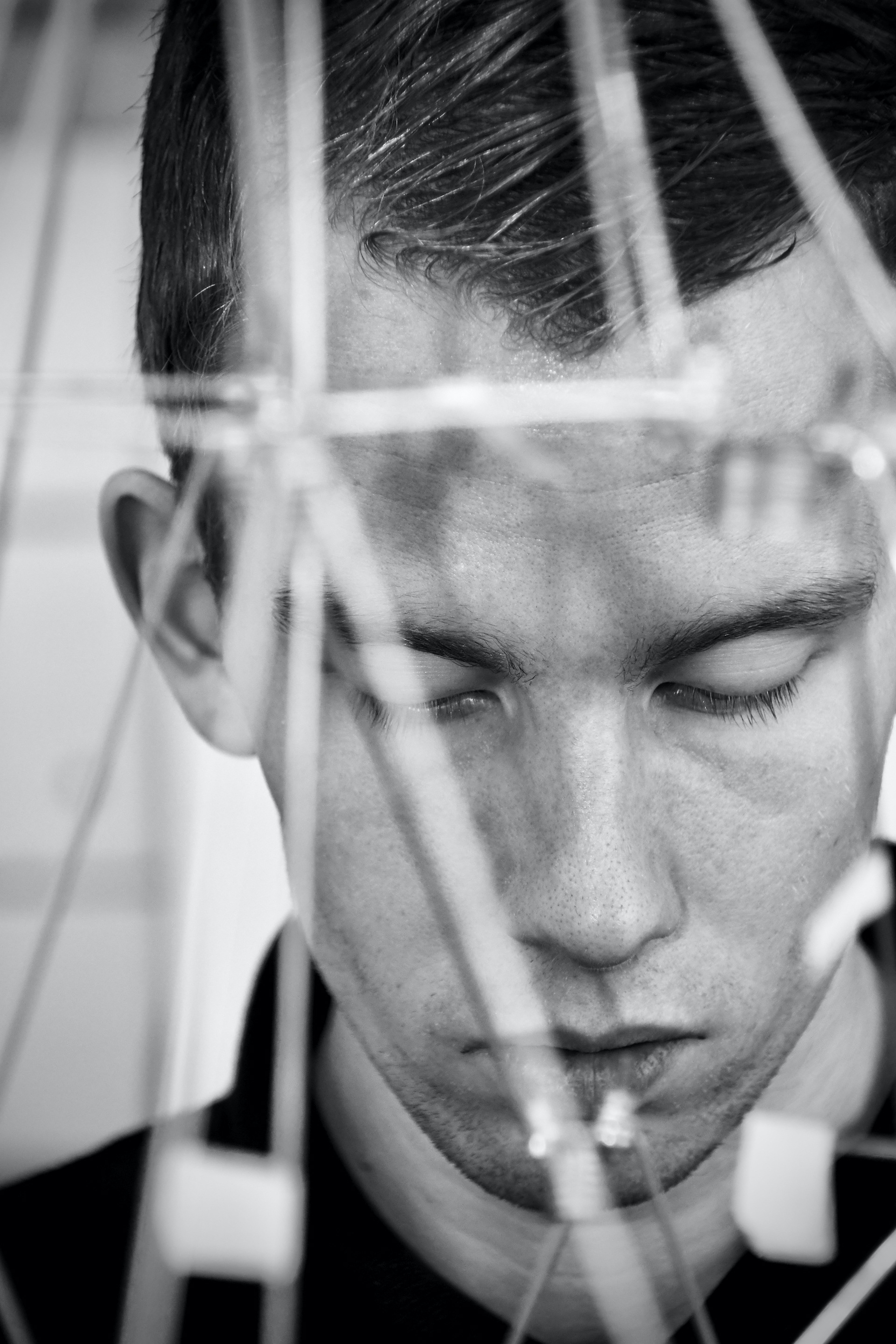 Reflective black-and-white portrait photographed through glass and layered reflections.