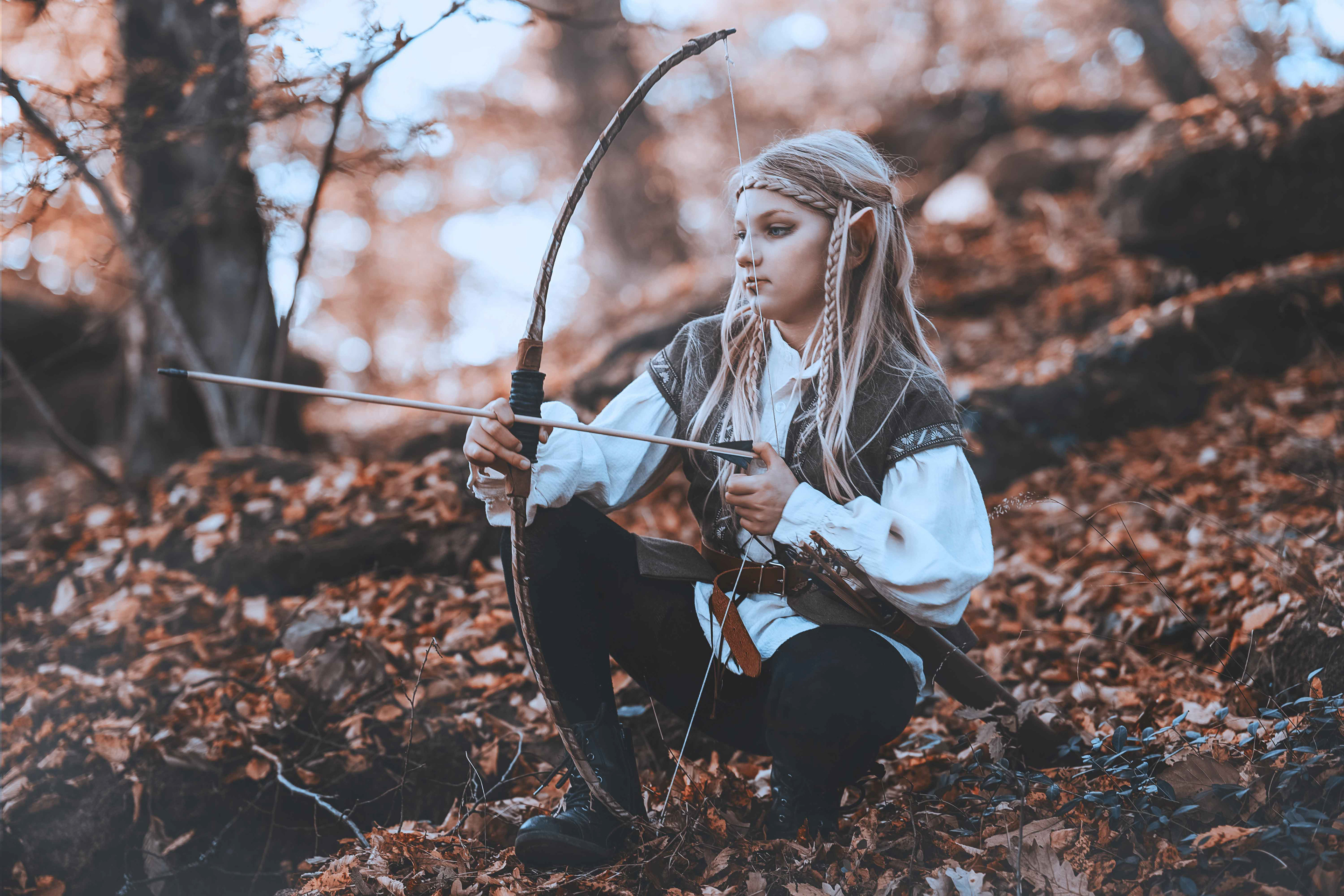 Nahaufnahme einer jungen Elfen Kriegerin im Profil bei einem Fantasy Cosplay Shooting von Medusa Fotografie im herbstlichen Wald. Zu sehen ist das detailreiche Fantasy Make-up, spitze Elfenohren, geflochtenes Haar mit Haarschmuck und eine helle Tunika