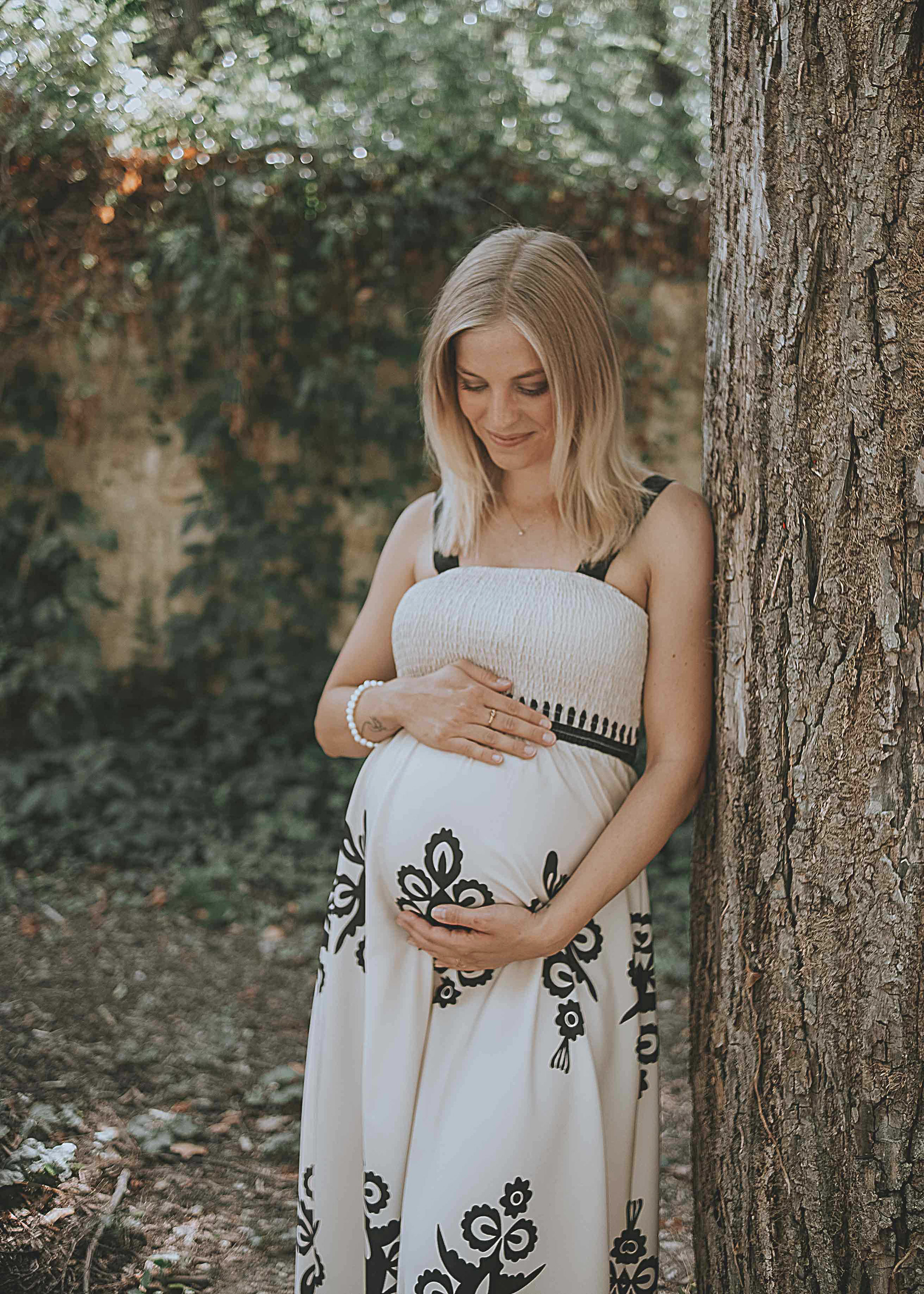 Emotionale Schwangerschaftsfotografie in der Natur, werdende Mutter betrachtet glücklich ihren Babybauch, professionell festgehalten von Medusa Fotografie