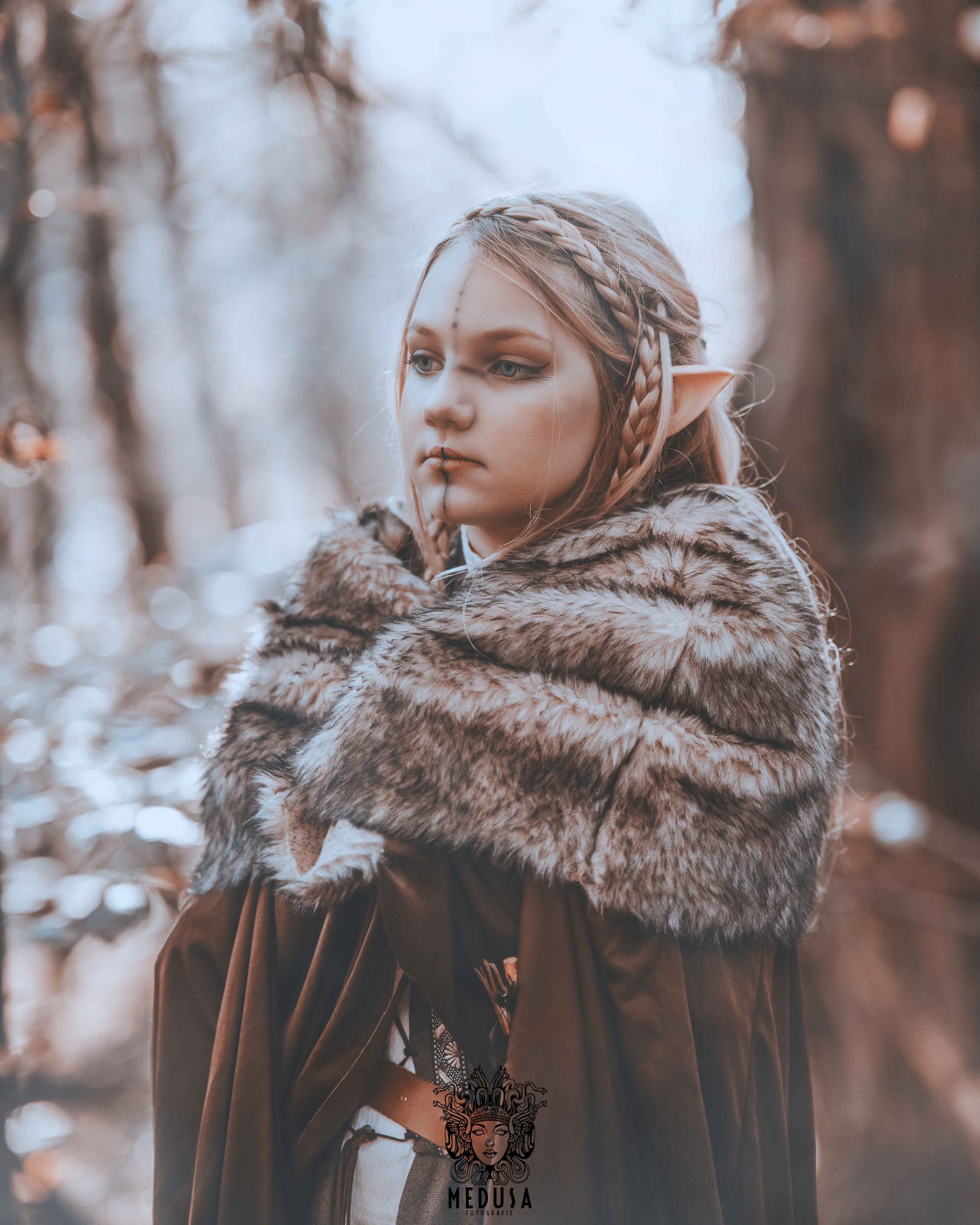 Nahaufnahme des Oberkörpers einer Elfen Kriegerin mit einem traditionellen Bogen im Anschlag. Das stimmungsvolle Outdoor Cosplay Shooting im herbstlichen Wald zeigt Details der Ausrüstung wie den Leder-Köcher und die Struktur des Bogens