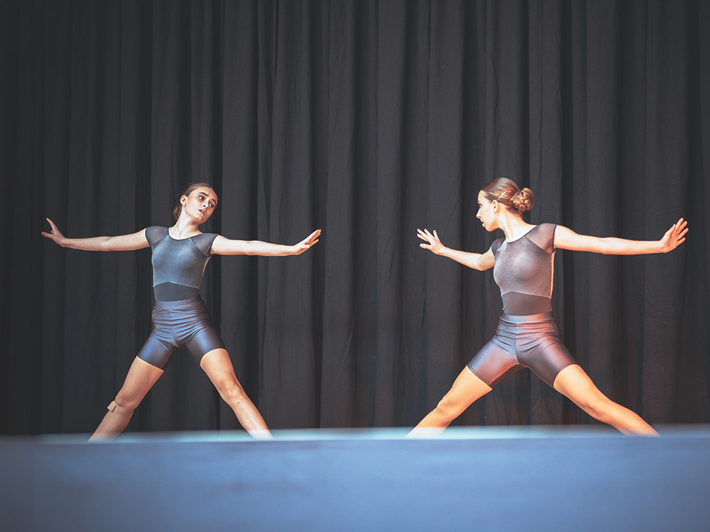 Eine Gruppe von Tänzerinnen in blauen Kostümen während einer ausdrucksstarken Bodenchoreografie, festgehalten von einem Eventfotograf.