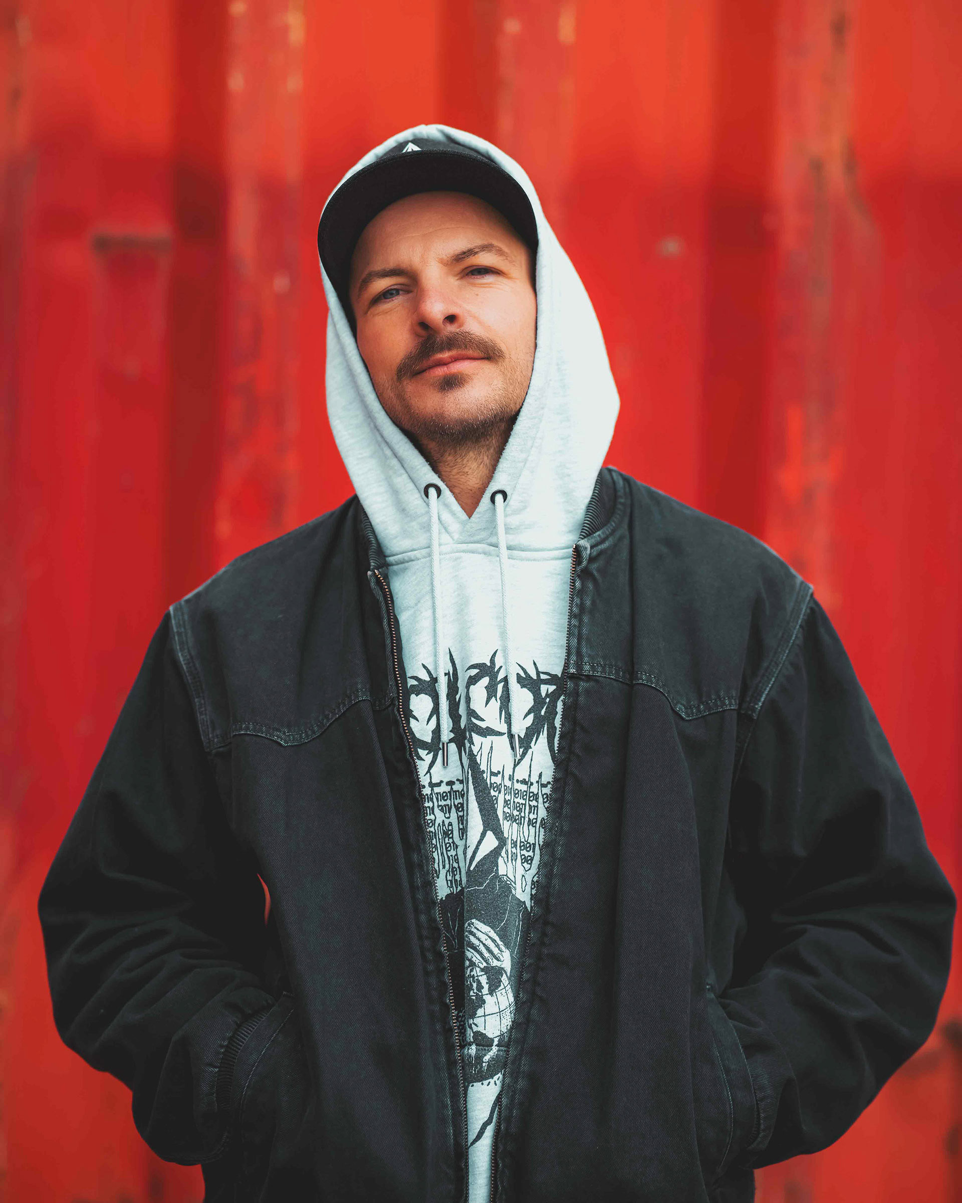 Urbanes Porträt eines Mannes vor einer leuchtend roten Containerwand im Hafengebiet Regensburg, aufgenommen von Medusa Fotografie