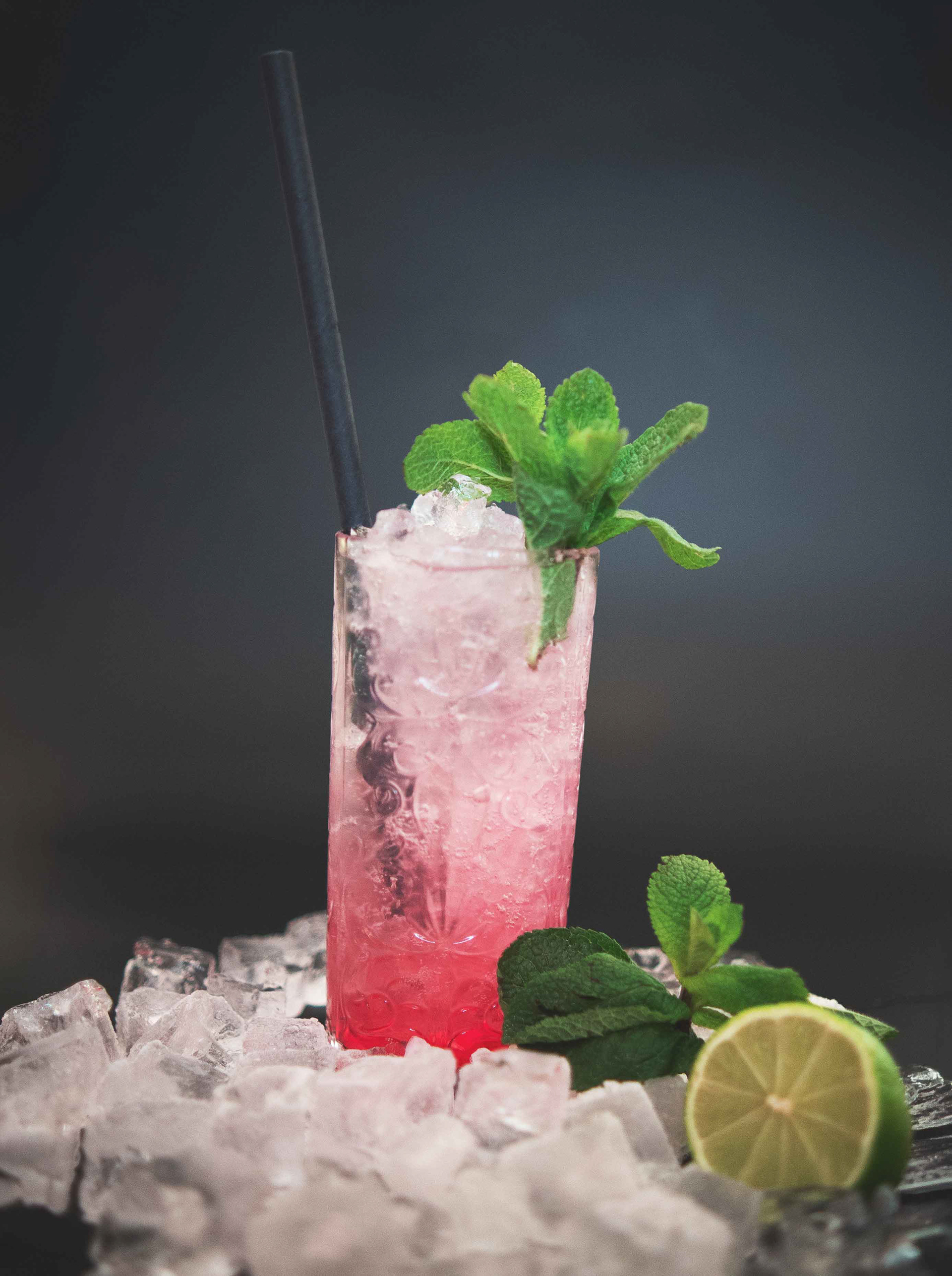 Hochwertiges Cocktail-Foto eines farbenfrohen Drinks mit Eiswürfeln und frischer Garnitur auf einer edlen Restaurant-Theke