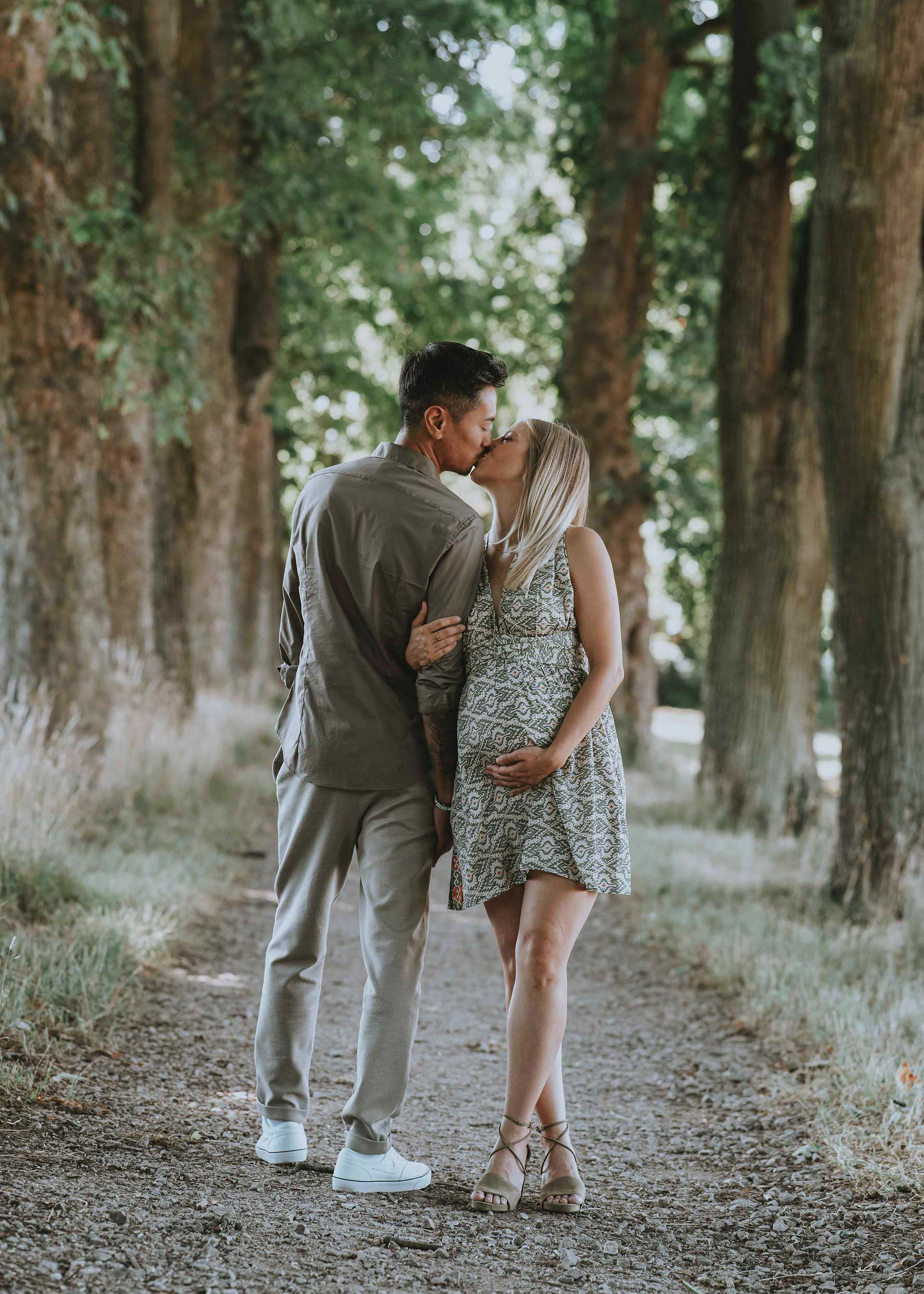 Romantischer Kuss eines Paares in einer herbstlichen Allee während eines Schwangerschaftsshootings in Regensburg