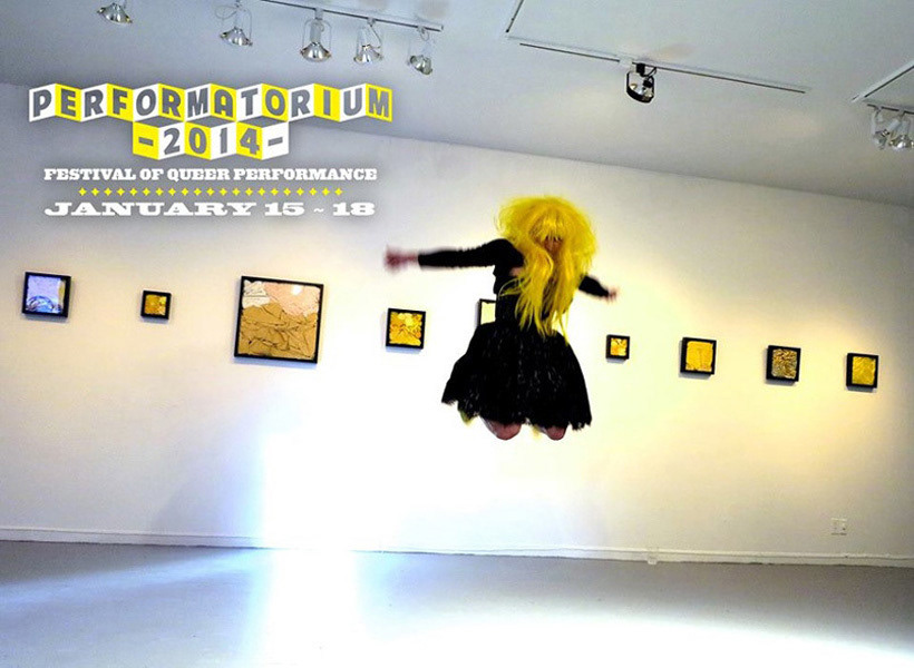 This image and the next four images are from a performance in Canada at LeLu Center for the arts. I am performing I'm Fine. I am wearing a black lace dress and a long yellow wig with yellow stilettos that have red and pink flowers with green leafs. Each photo is a moment from the live performance. I am performing in the gallery space where my solo show was installed unspeakable truths. Behind me are shadow box frames that are filled with the objects from my short film the yellow wallpaper.