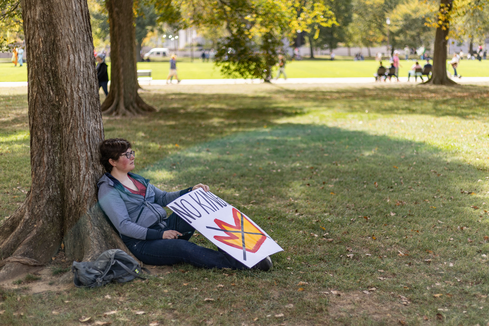 A protestor rests under a tree on the National Mall during the No Kings protest in Washington, D.C. on Oct. 18, 2025. Over 7 million people across the country marched against recent actions by President Trump, from the immigration crackdown to the general state of the economy.