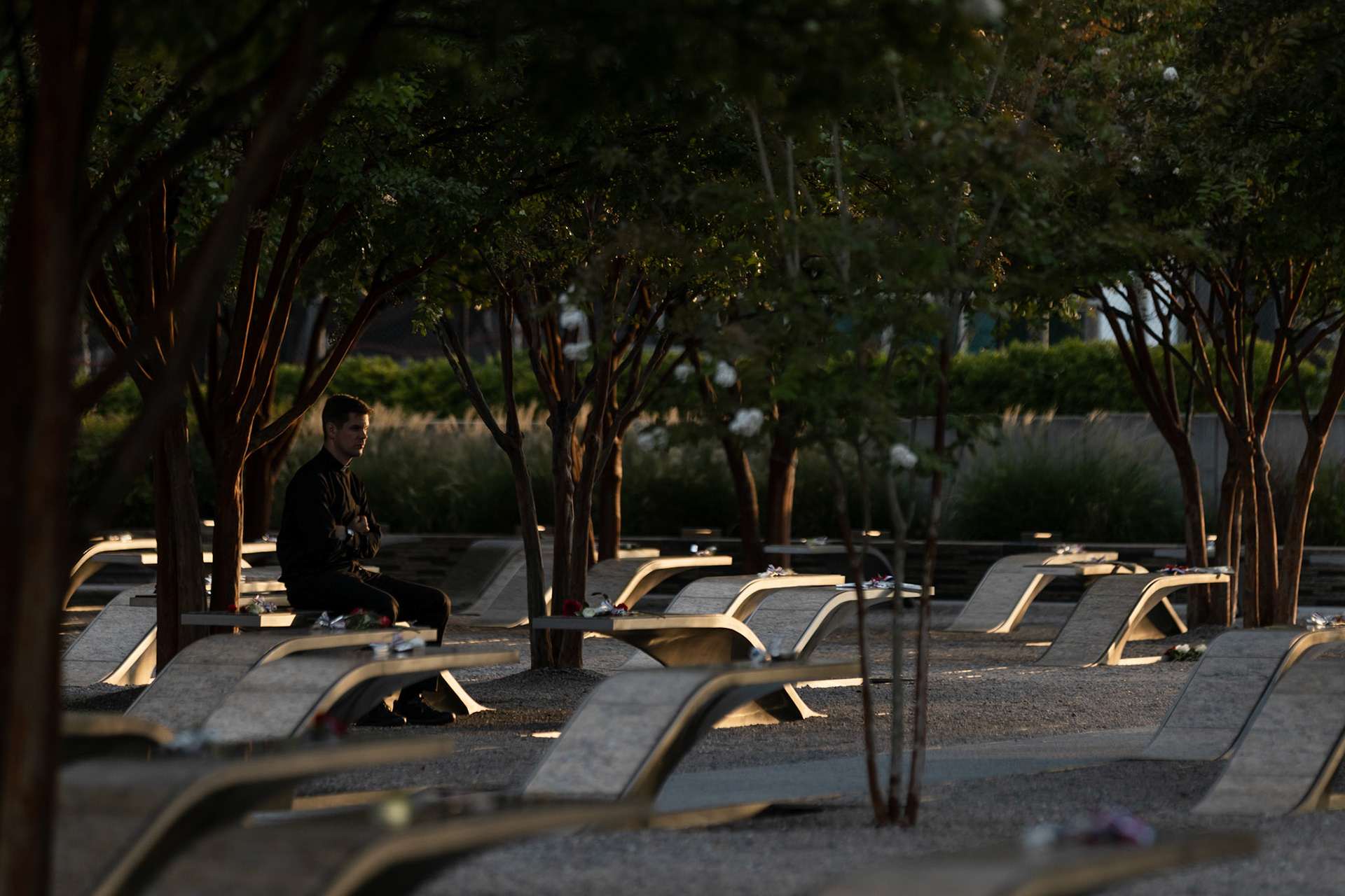 ARLINGTON, VIRGINIA - SEPTEMBER 11: A reverend sits on one of the illuminated benches dedicated to a victim of the attack at the 9/11 Pentagon Memorial on Sept. 11, 2025. Completed in 2008, the site consists of 184 illuminated benches arranged by age, each one dedicated to a victim either in the building or on the flight at the time of the crash.