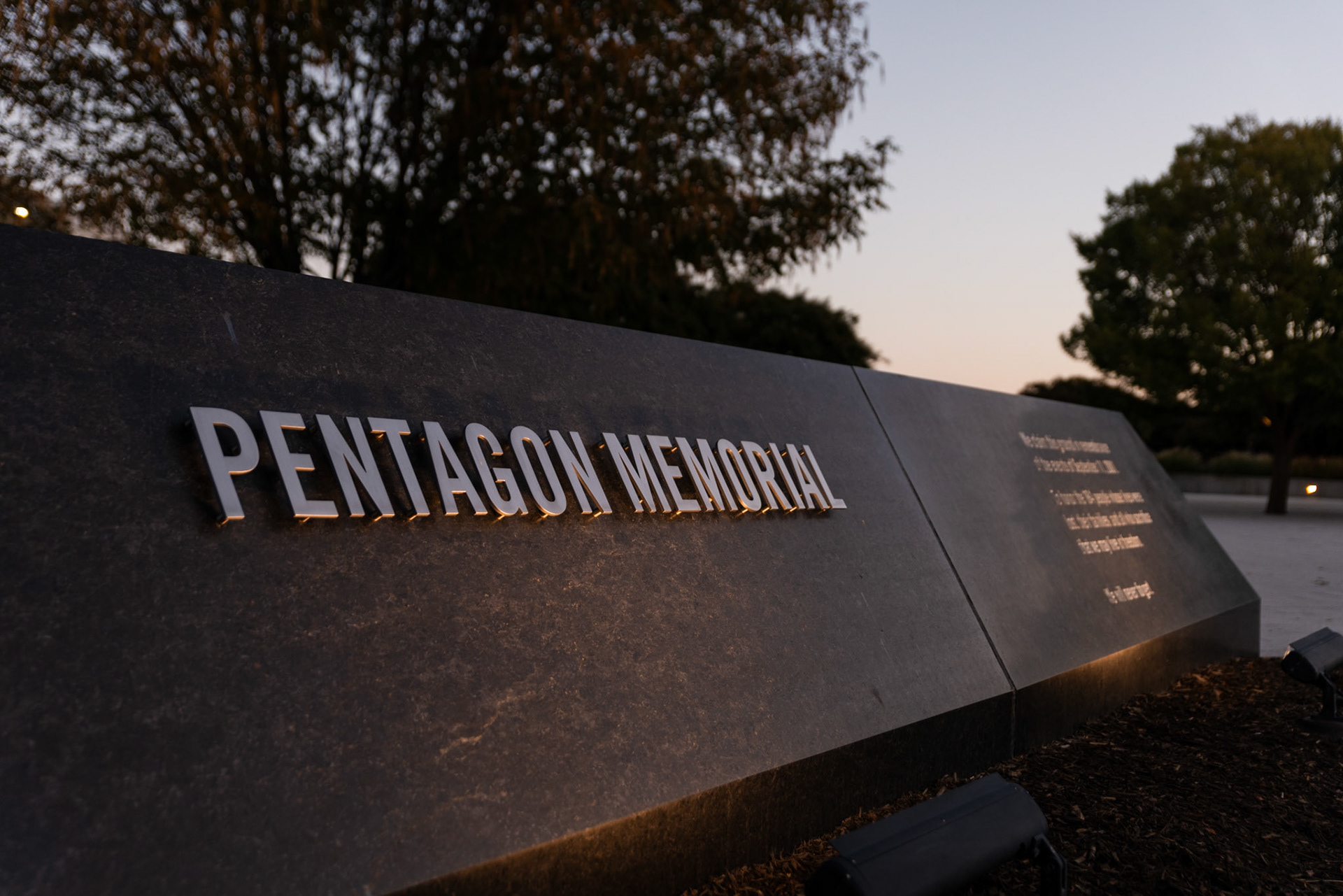 ARLINGTON, VIRGINIA - SEPTEMBER 12: A plaque welcoming visitors sits at the entrance to the 9/11 Pentagon Memorial as the sun rises on Sept. 12, 2025. Located on the southwest side of the Pentagon, the memorial honors the 184 victims who died both in the building and on the American Airlines flight that crashed there.