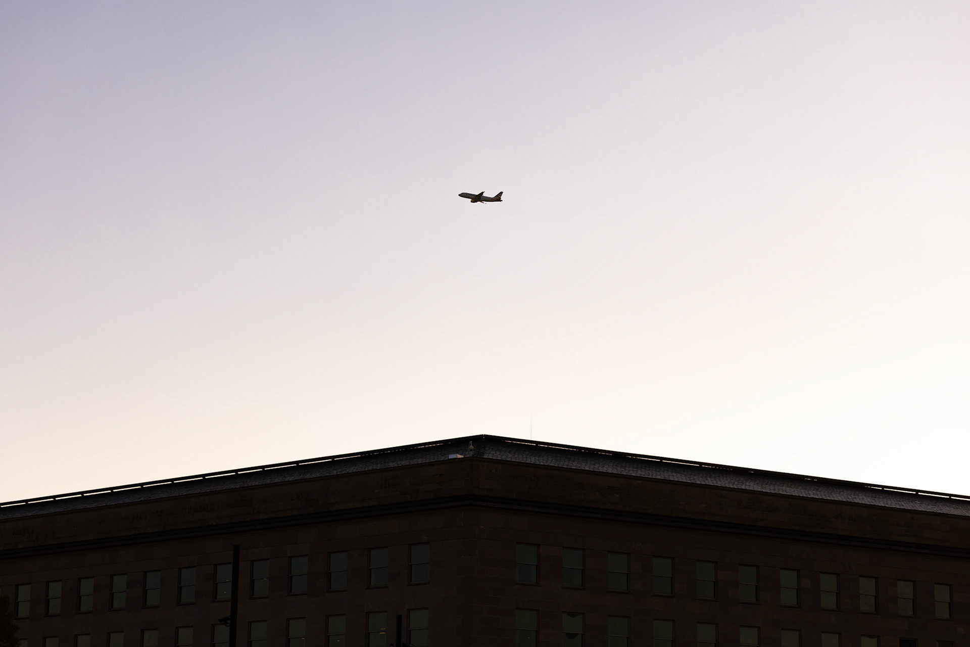 ARLINGTON, VIRGINIA - SEPTEMBER 12: As the sun rises over the Pentagon, an American Airlines plane departs from Reagan National Airport on Sept. 12, 2025. Completed in 2008, the site consists of 184 illuminated benches arranged by age, each one dedicated to a victim either in the building or aboard American Airlines flight 77.