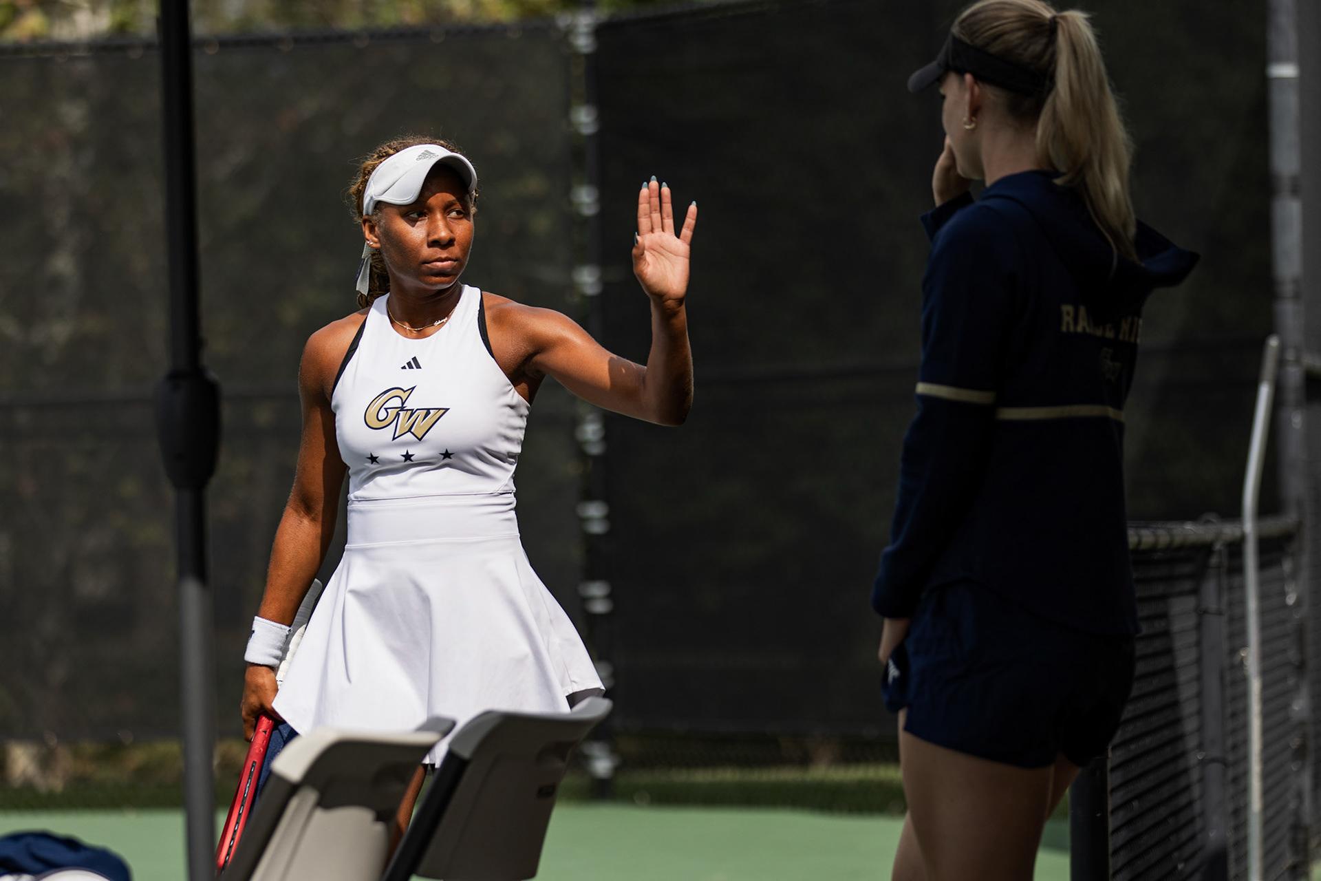 COLLEGE PARK, MARYLAND - SEPTEMBER 20: GW junior Solange Skeene high fives Assistant Coach Stella Wiesemann between sets of her semifinals singles match against Norfolk State University’ Elena Prado at the Bedford Cup in College Park, Md. on Sept. 20, 2025. Skeene won both sets 6-1, advancing to victory in the finals on Sunday.