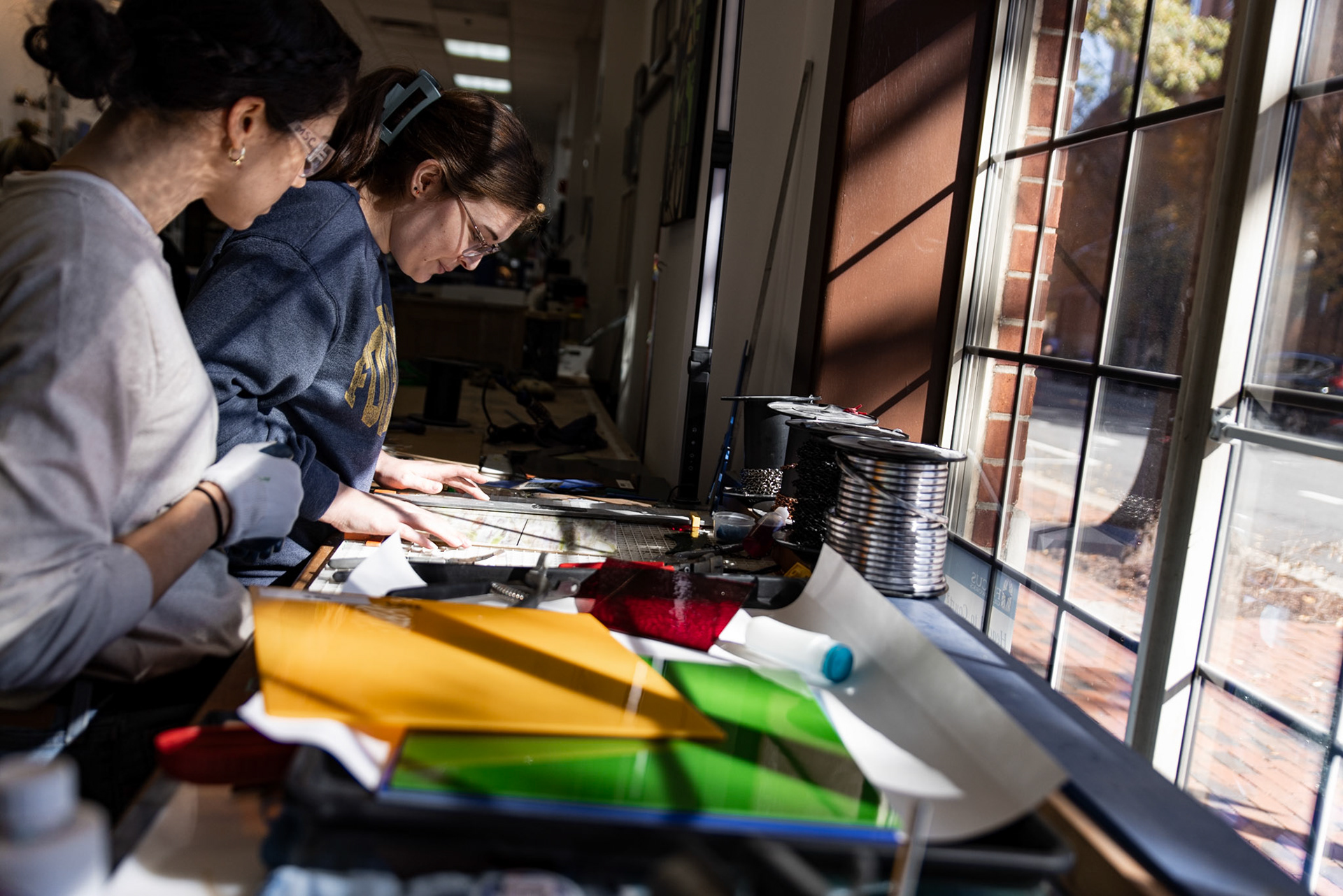 Mare' Fiscus, manager and teacher at Fiscus Glassworks, demonstrates a process for cleanly cutting a sheet of glass during a basic stained glass making class in Alexandria, Va. on Nov. 08, 2025.