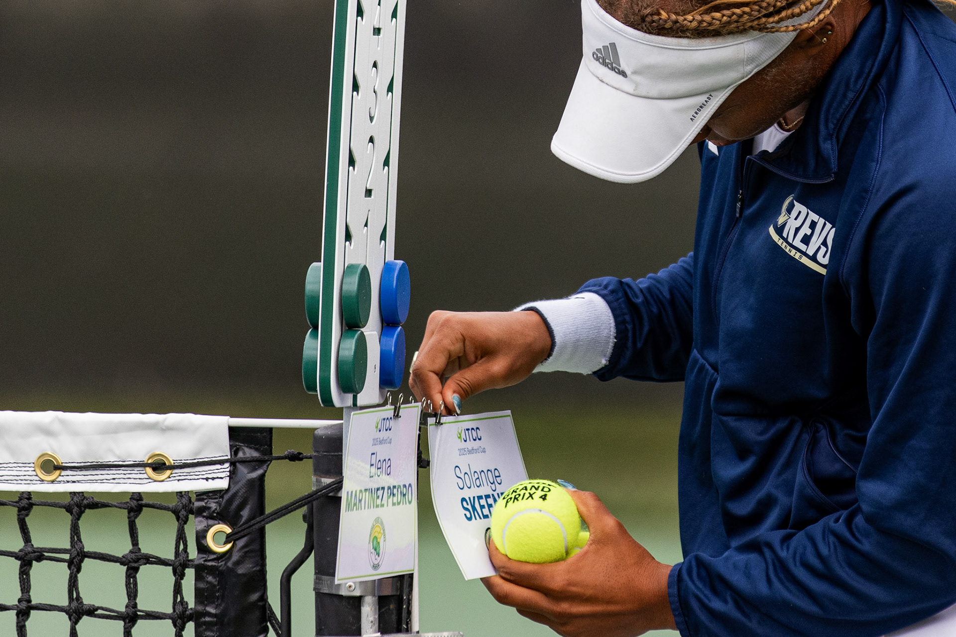 COLLEGE PARK, MARYLAND - SEPTEMBER 20: GW tennis junior Solange Skeene hangs her name placard at the edge of the net ahead of her singles match against Norfolk State University’s Elena Prado in the Bedford Cup semifinals in College Park, Md. on Sept. 20, 2025. Having led the tennis team in most singles wins last season, Skeene won in straight sets when facing Prado and continued to win the flight two north bracket.