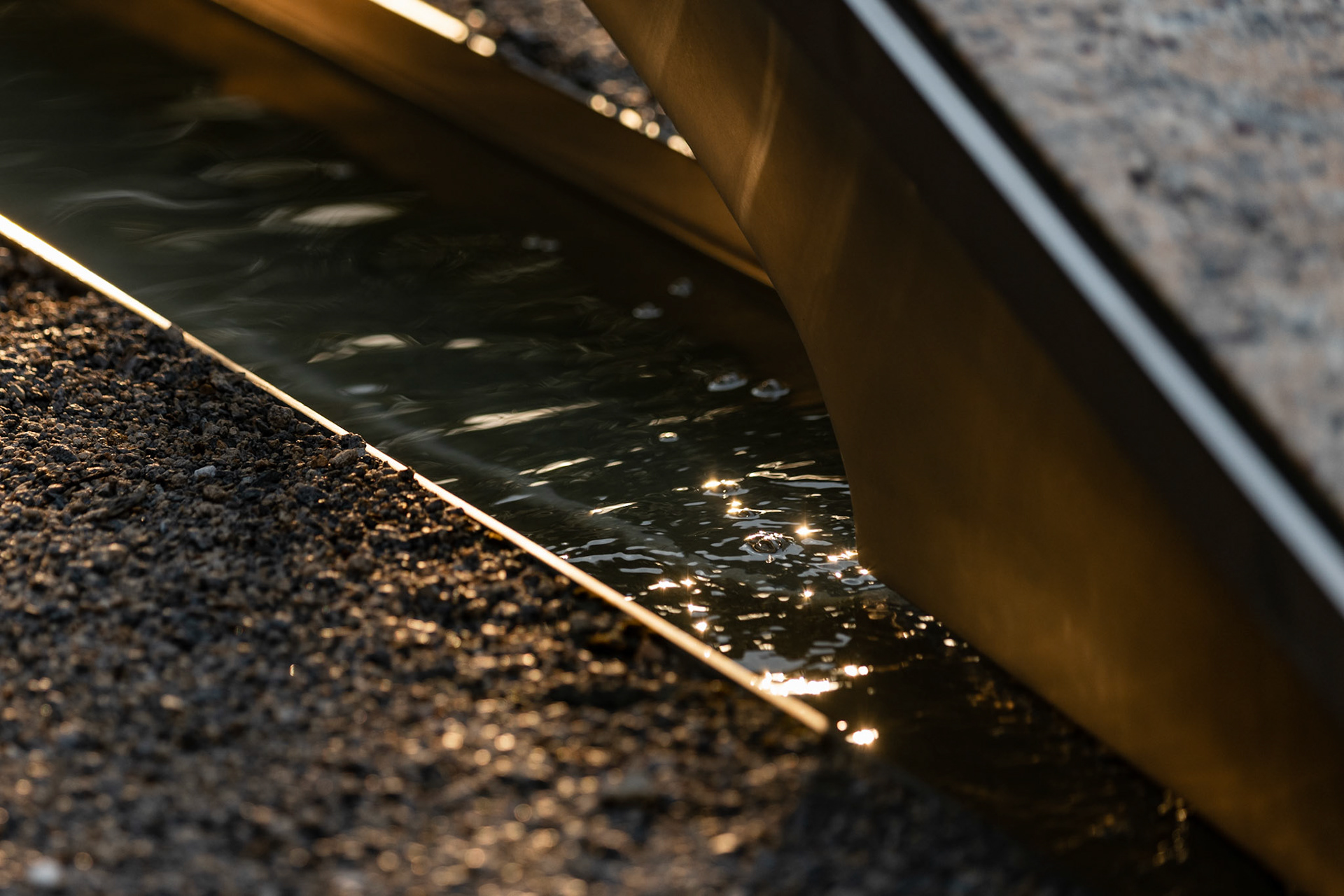 ARLINGTON, VIRGINIA - SEPTEMBER 11: Water ripples beneath one of the tribute benches as the sun sets over the 9/11 Pentagon Memorial on Sept. 11, 2025. Completed in 2008, the site consists of 184 illuminated benches arranged by age, each one dedicated to a victim either in the building or on the flight at the time of the crash, with a shallow pool of water underneath.