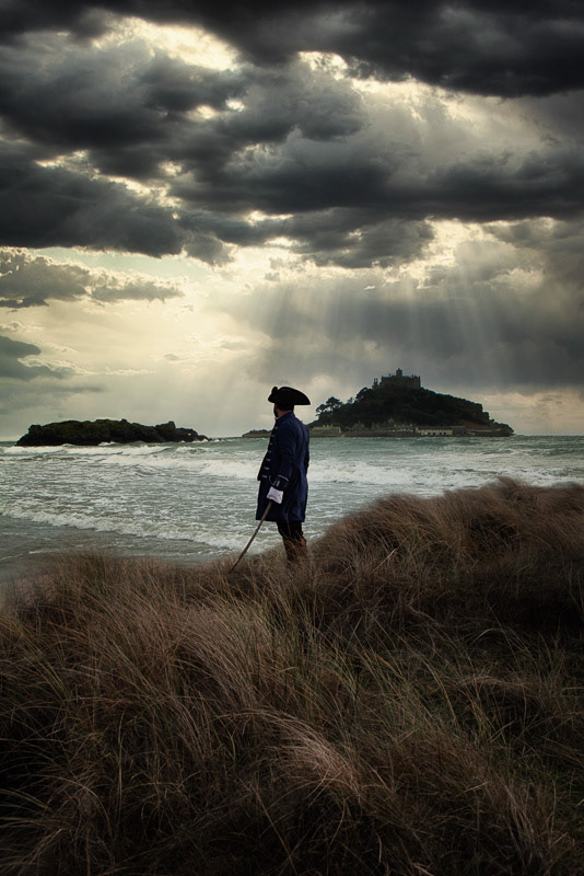 man with flintlock looking out at St Michael's Mount in Cornwall