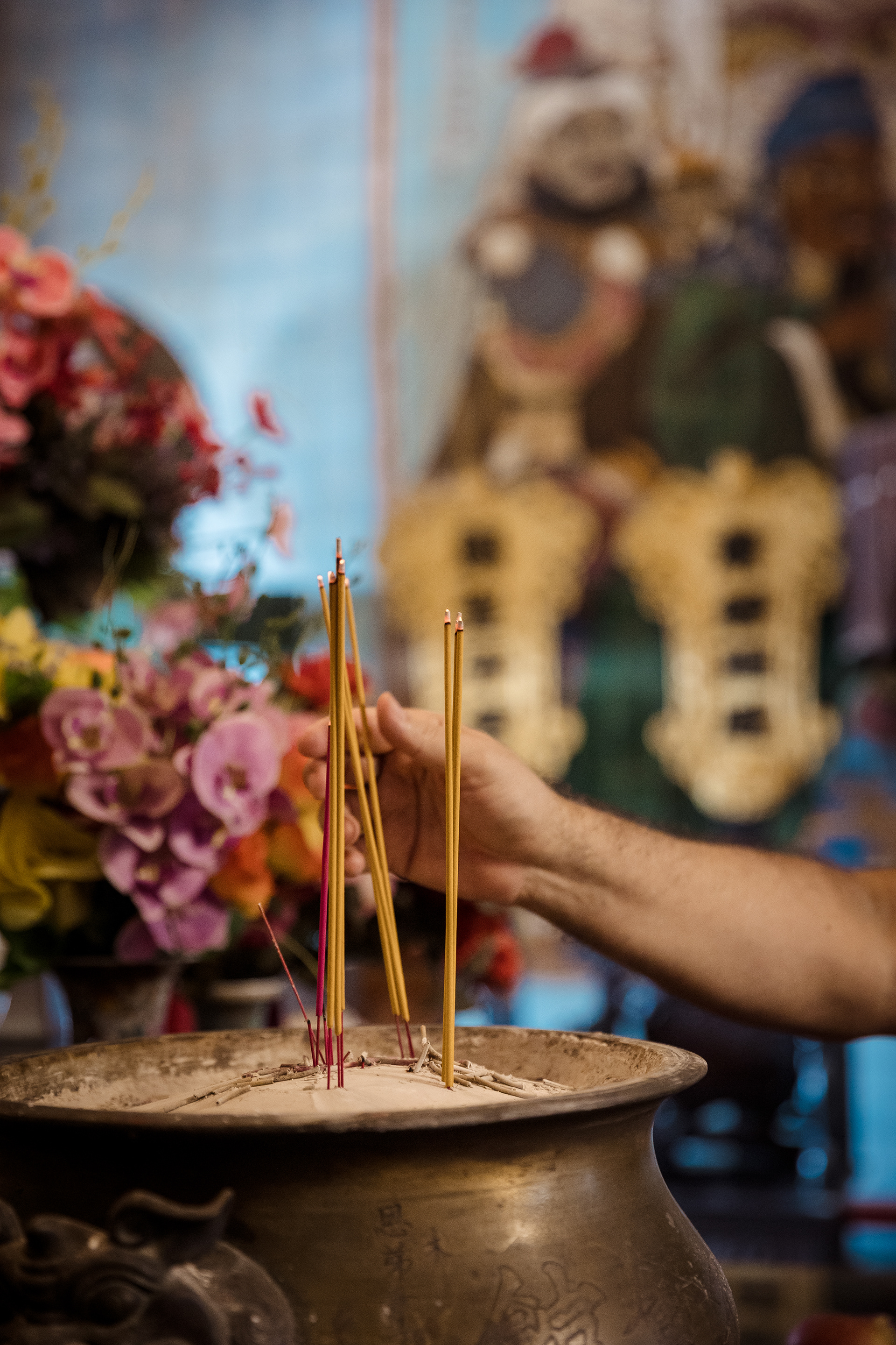 A worshipper places incense into a pot during a prayer ritual at Yan Wo Temple in Panama City's historic Casco Antiguo neighborhood. Chinatown, Panama. July 20, 2025.