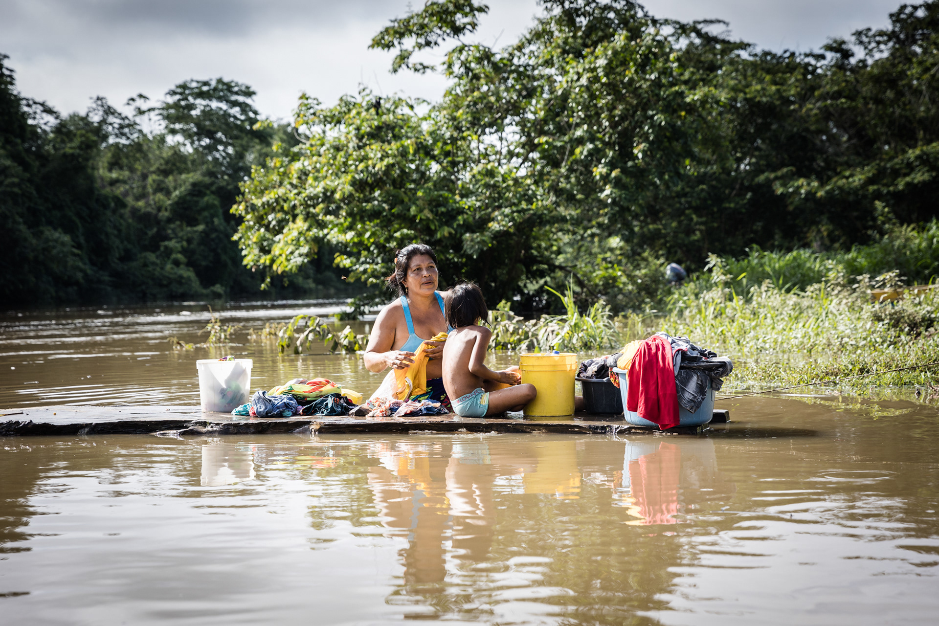 An Emberá woman washes clothes at the banks of the Turquesa River, continuing daily life amidst the changes in the community.