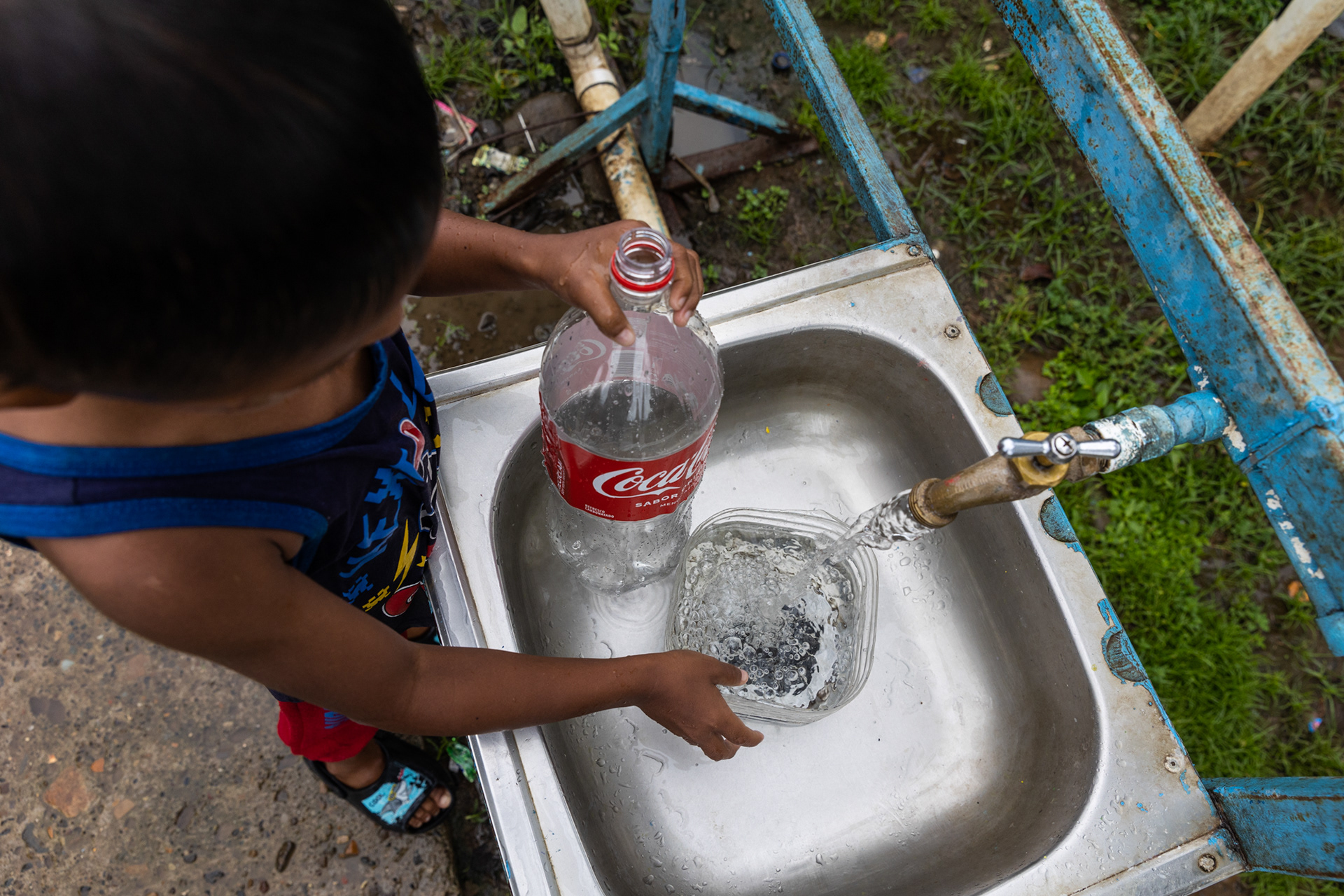A child gathers water from a faucet system installed by international aid organizations, improving infrastructure in the community.