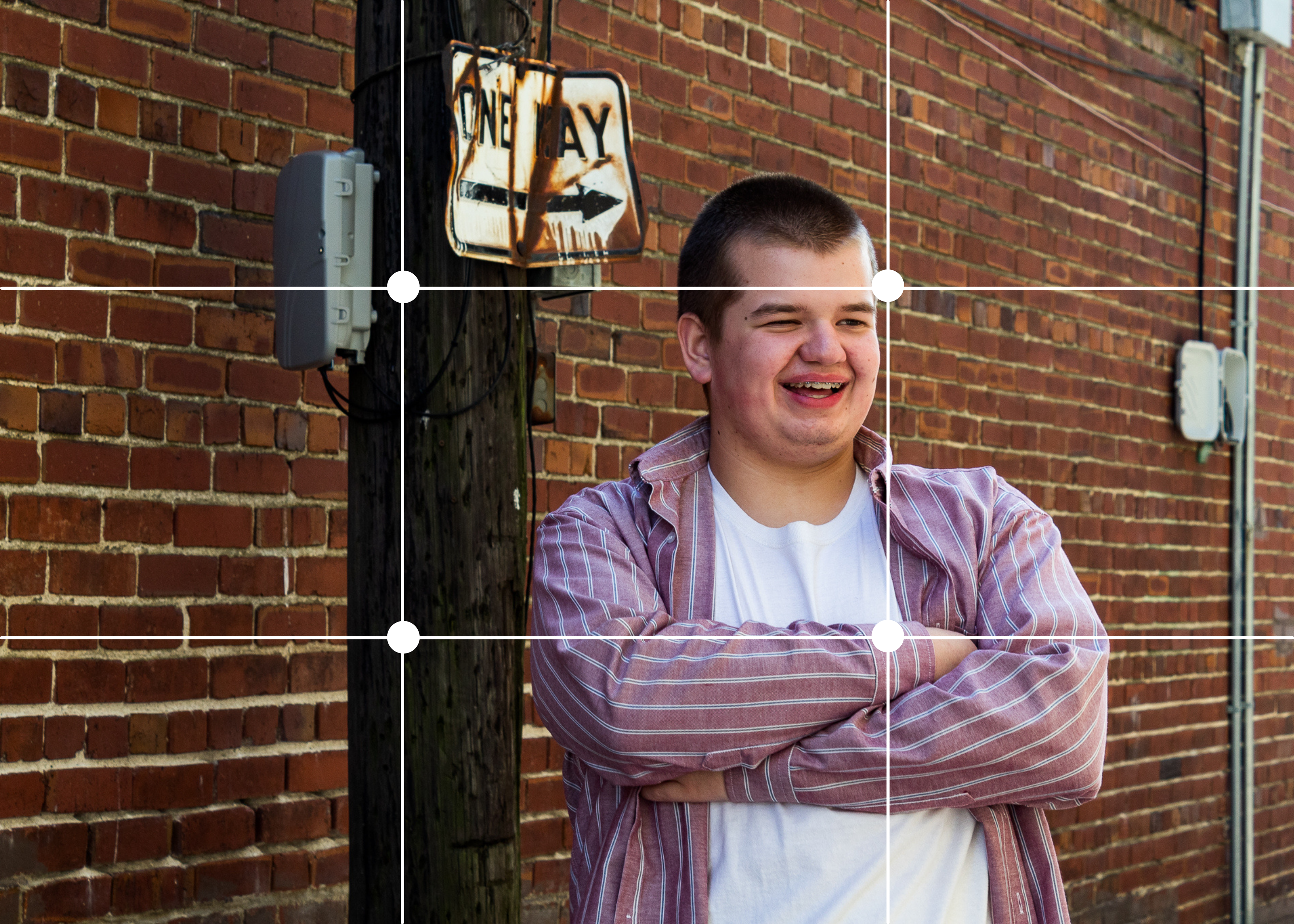 Rogan leans on a light pole in this image. Both Rogan and the light pole are placed at intersections of the grid for the rule of thirds.