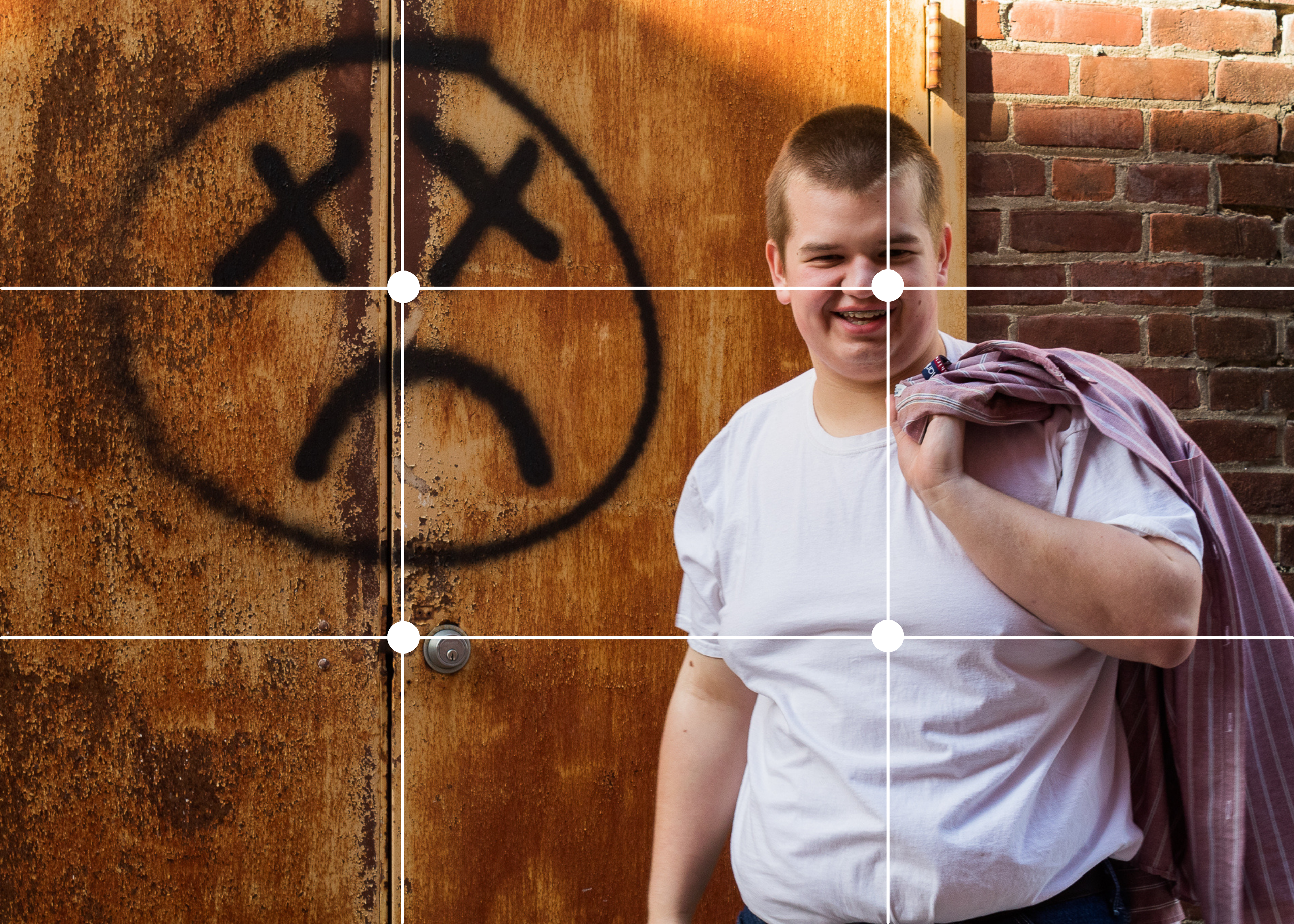 The intersections of the grid for the rule of thirds draw us to Rogan, and also the graffitied face on the door beside him.