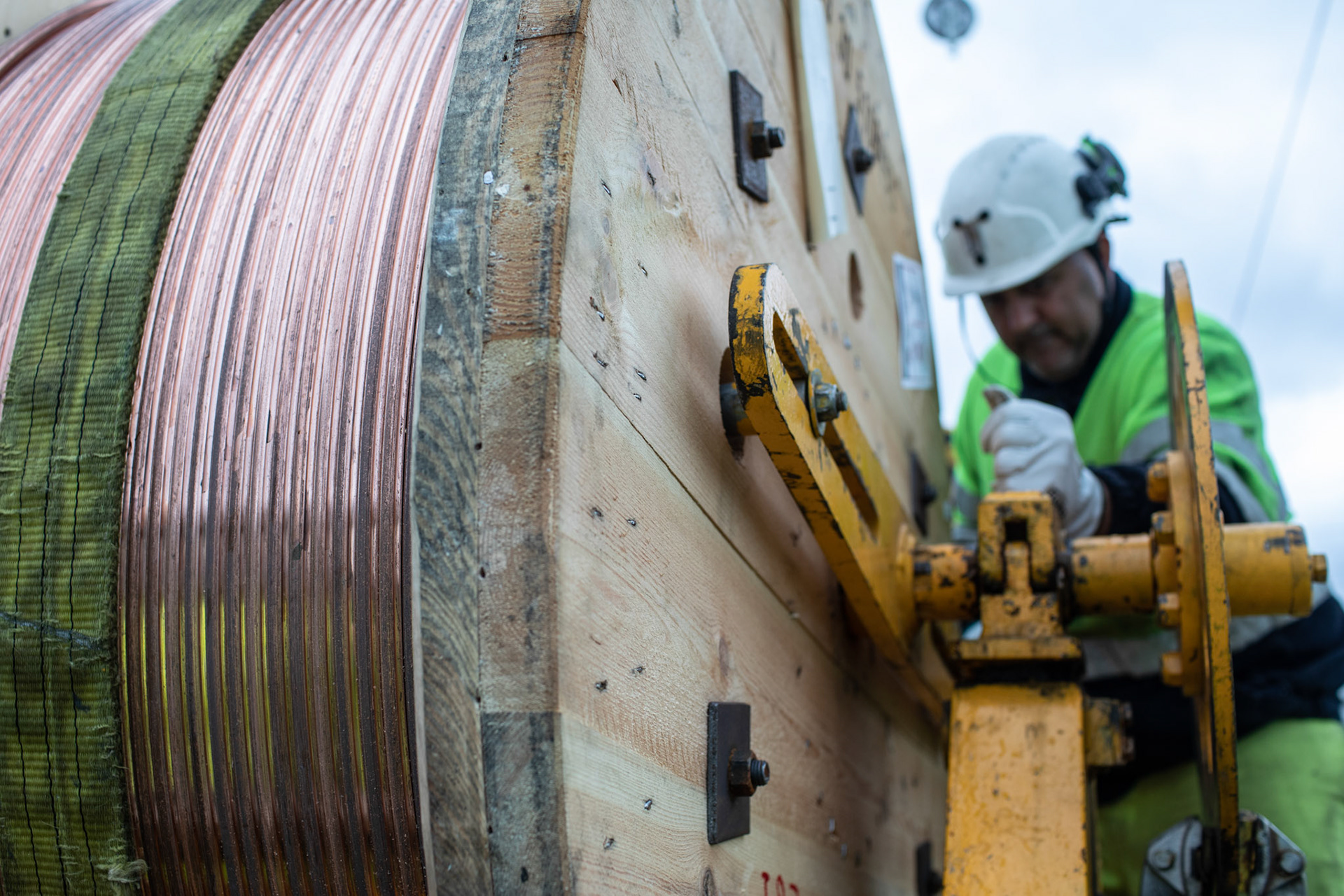 Festing av spole på trommel med kjøyreledning. Arbeidere frå entrepenøren Elecnor monterar kjøyreledning (OCS) til Bybanens Linje 2 langs Mindemyren. Fotografert 23.06.2022